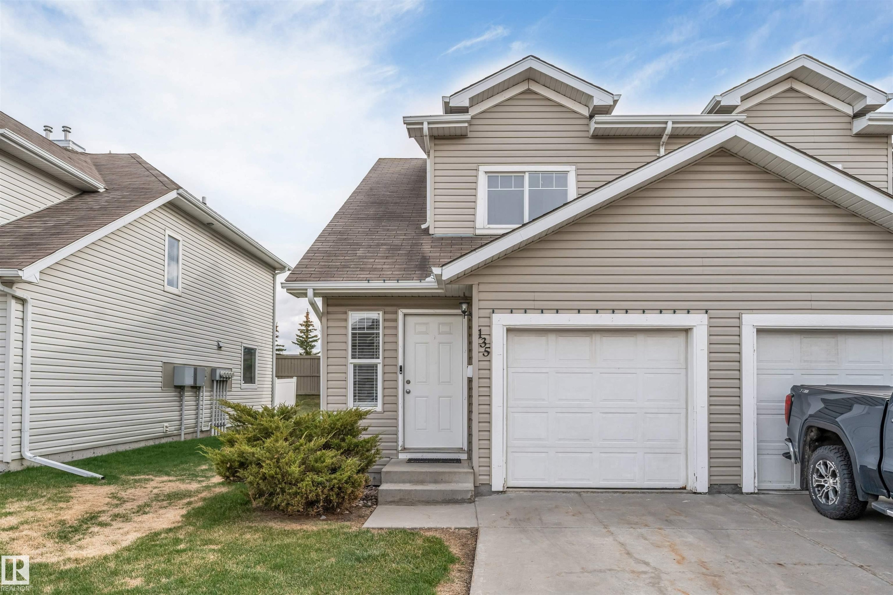 Residential property featuring beige horizontal siding, an attached single-car garage, and a concrete driveway - 135 150 Edwards Drive, Edmonton, AB - Outdoor
