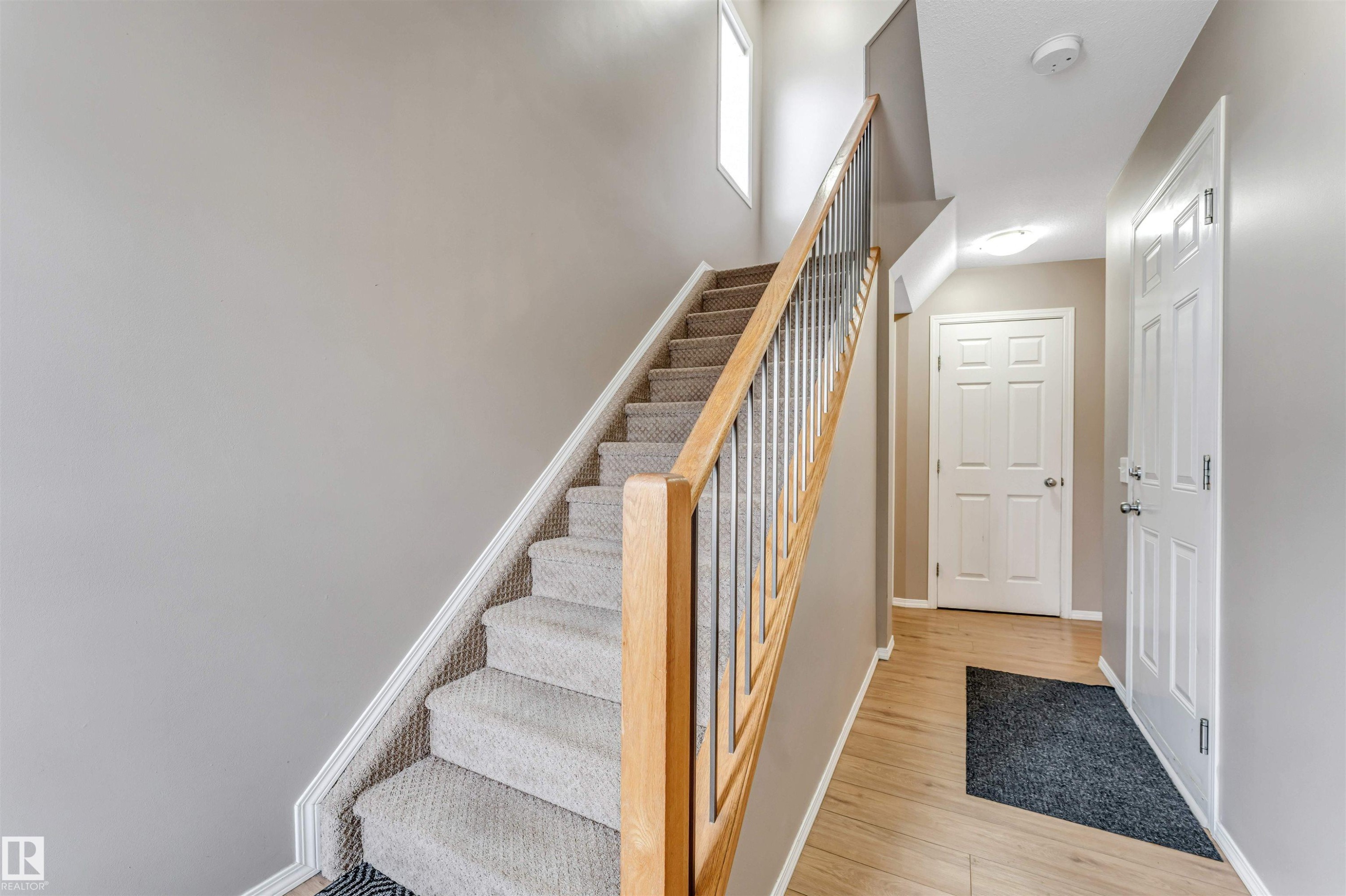 Staircase featuring light wood handrails, metal spindles, and carpeted treads - 135 150 Edwards Drive, Edmonton, AB - Indoor Photo Showing Other Room