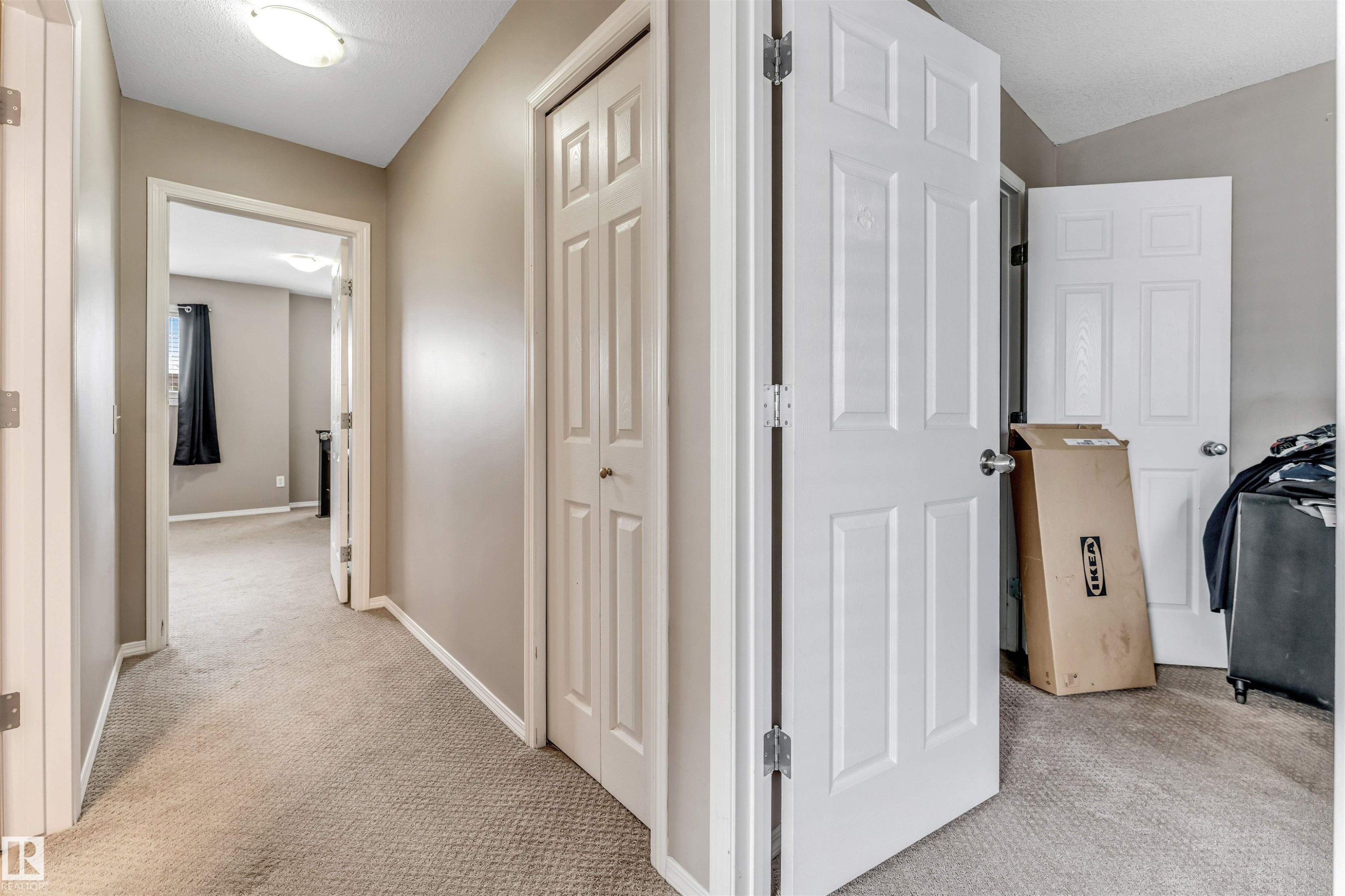 Neutral-toned hallway featuring light beige walls and complementing carpeted flooring - 135 150 Edwards Drive, Edmonton, AB - Indoor Photo Showing Other Room