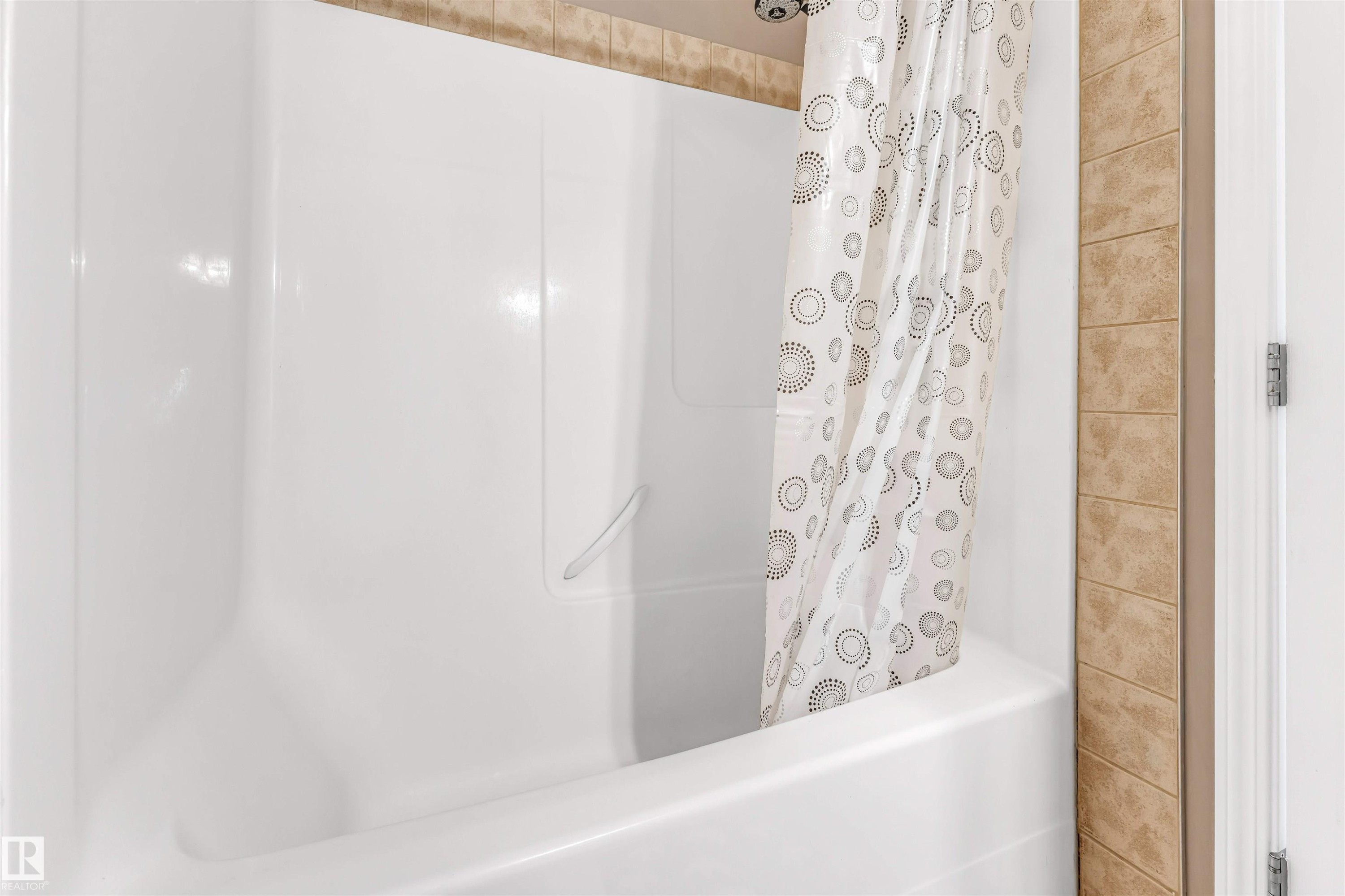 Shower-over-tub combination with white acrylic surround and integrated grab bar - 135 150 Edwards Drive, Edmonton, AB - Indoor Photo Showing Bathroom