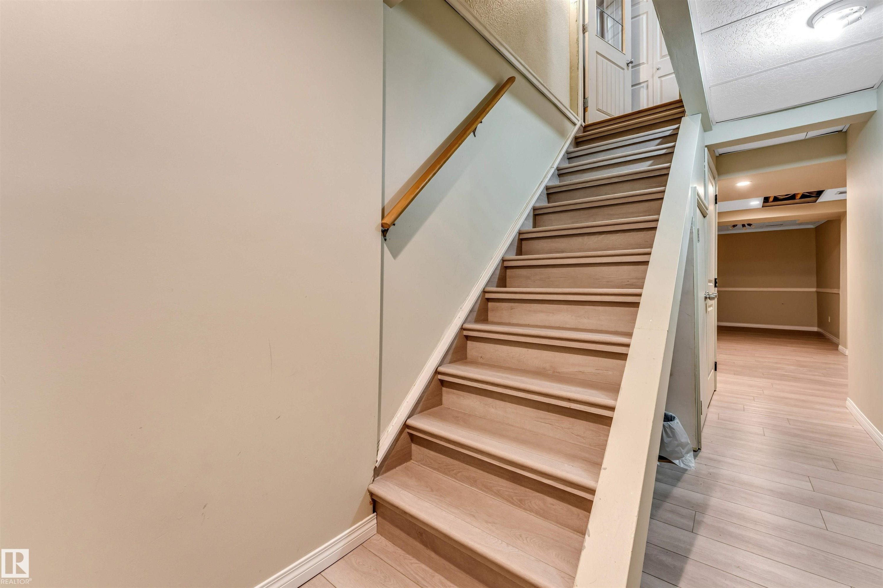 Hardwood staircase with natural wood handrail - 135 150 Edwards Drive, Edmonton, AB - Indoor Photo Showing Other Room