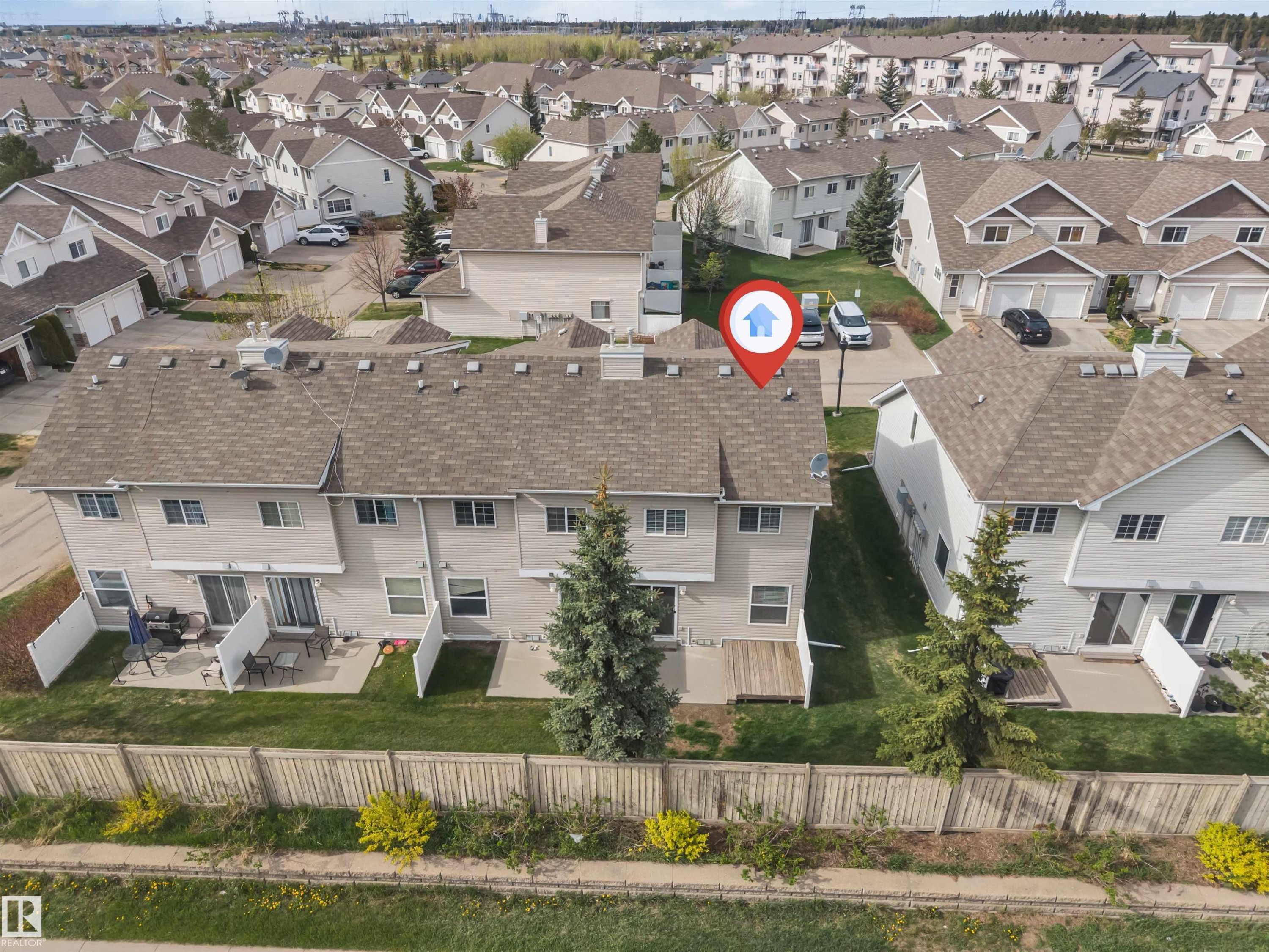 Townhouse featuring a neutral-toned exterior, gabled roofline with asphalt shingles, and multiple windows - 135 150 Edwards Drive, Edmonton, AB - Outdoor