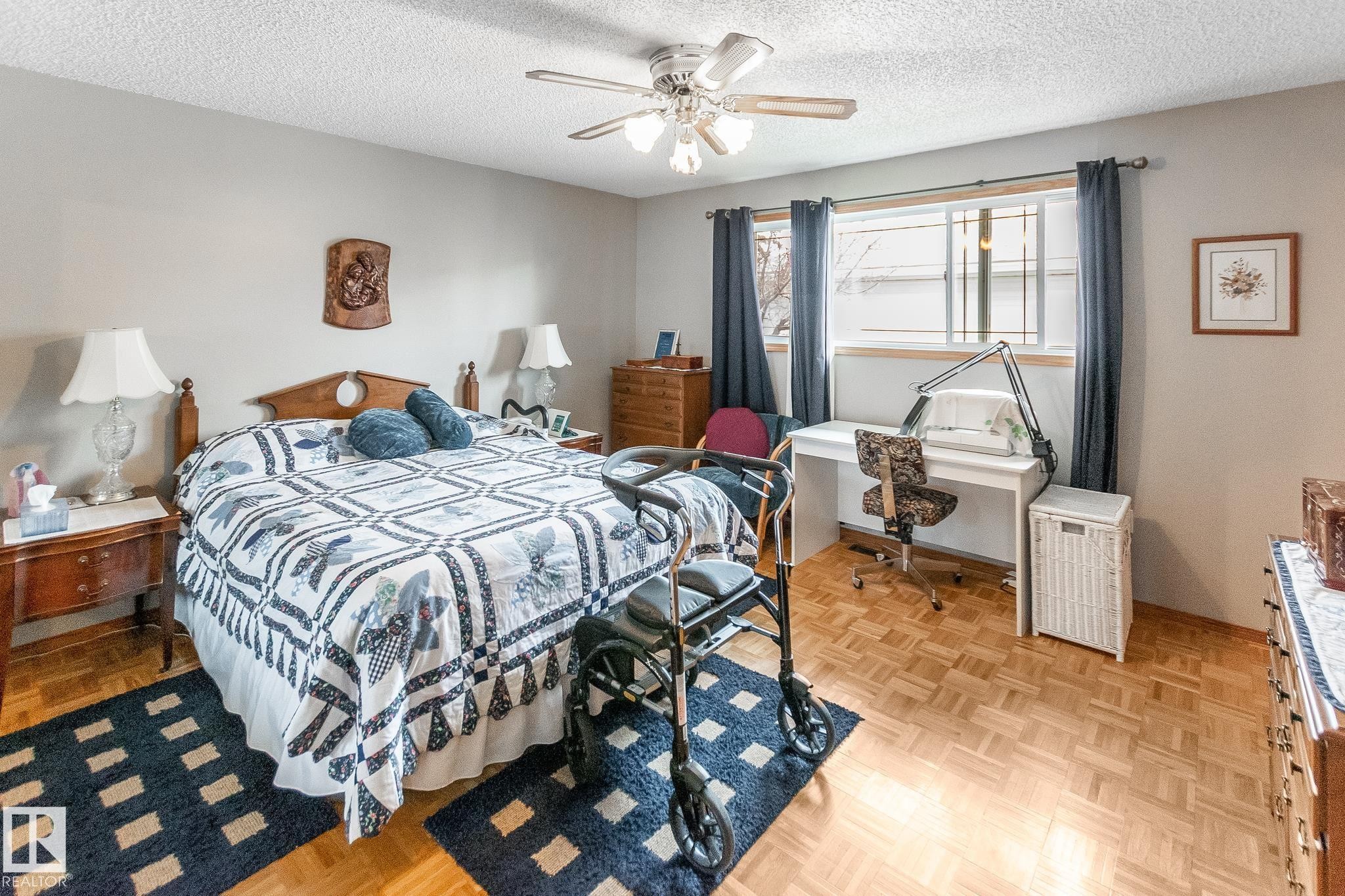 Room featuring wood-finish parquet flooring, a ceiling fan with integrated lighting, and multiple windows with trim - 4611 Lakeshore Drive, Bonnyville Town, AB - Indoor Photo Showing Bedroom