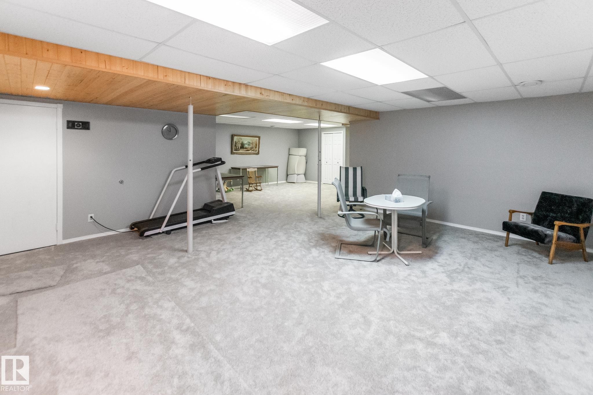 Spacious finished room with light-colored carpeting, drop ceiling with recessed lighting, and a wood-finish ceiling accent - 4611 Lakeshore Drive, Bonnyville Town, AB - Indoor Photo Showing Basement