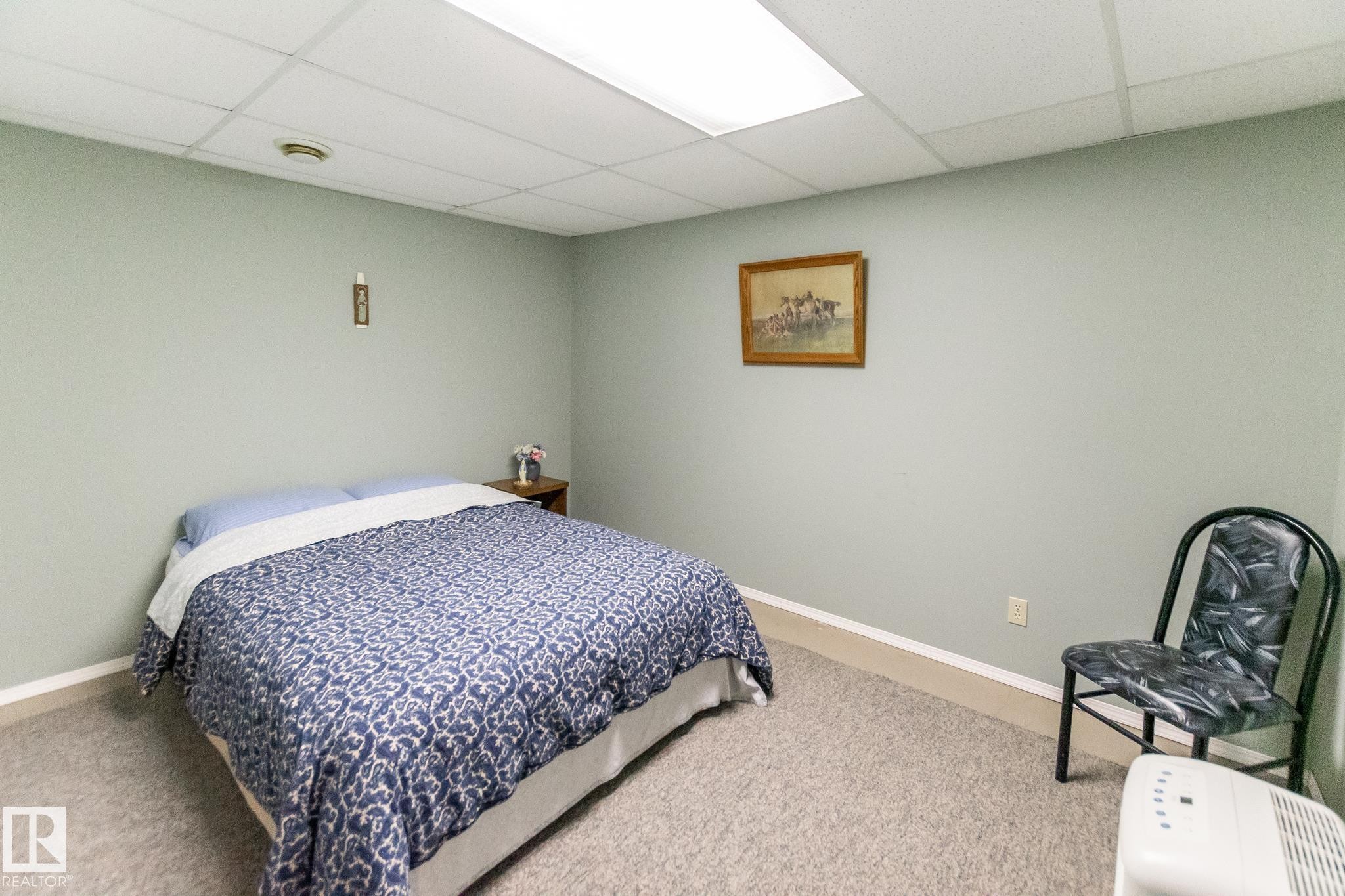 Carpeted room with a drop ceiling featuring integrated lighting and a neutral wall color - 4611 Lakeshore Drive, Bonnyville Town, AB - Indoor Photo Showing Bedroom