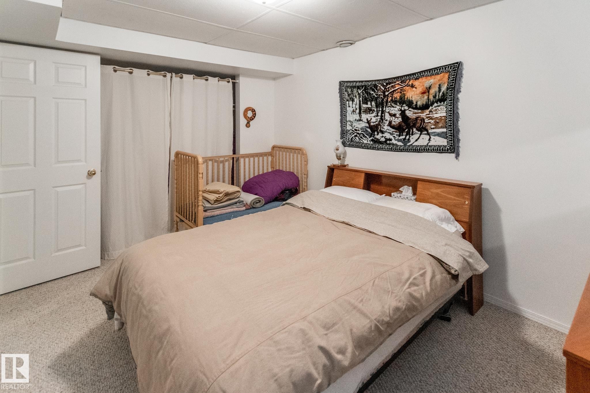 Carpeted room with a paneled white door and a wooden bed frame featuring a built-in headboard - 4611 Lakeshore Drive, Bonnyville Town, AB - Indoor Photo Showing Bedroom