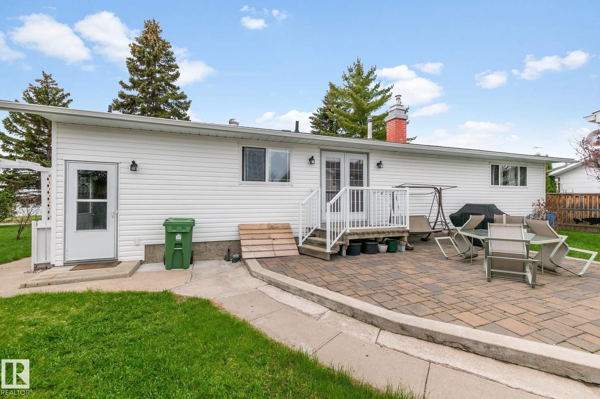 Rear exterior featuring white vinyl siding, a paver patio, and a white deck with railings - 4611 Lakeshore Drive, Bonnyville Town, AB - Outdoor With Exterior