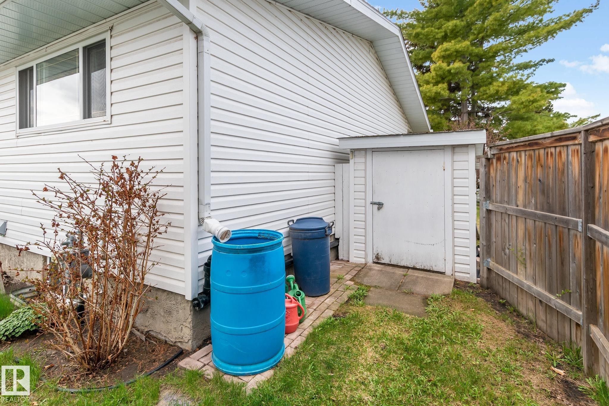 White vinyl siding exterior with an integrated storage shed and a wood fence - 4611 Lakeshore Drive, Bonnyville Town, AB - Outdoor With Exterior
