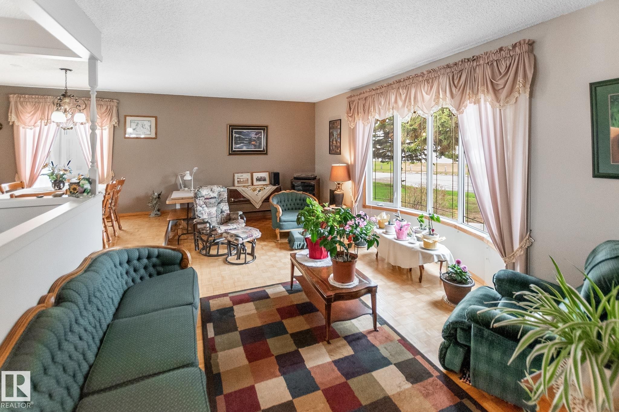 Spacious living area featuring wood-finish flooring, neutral wall paint, and a large bay window - 4611 Lakeshore Drive, Bonnyville Town, AB - Indoor Photo Showing Living Room