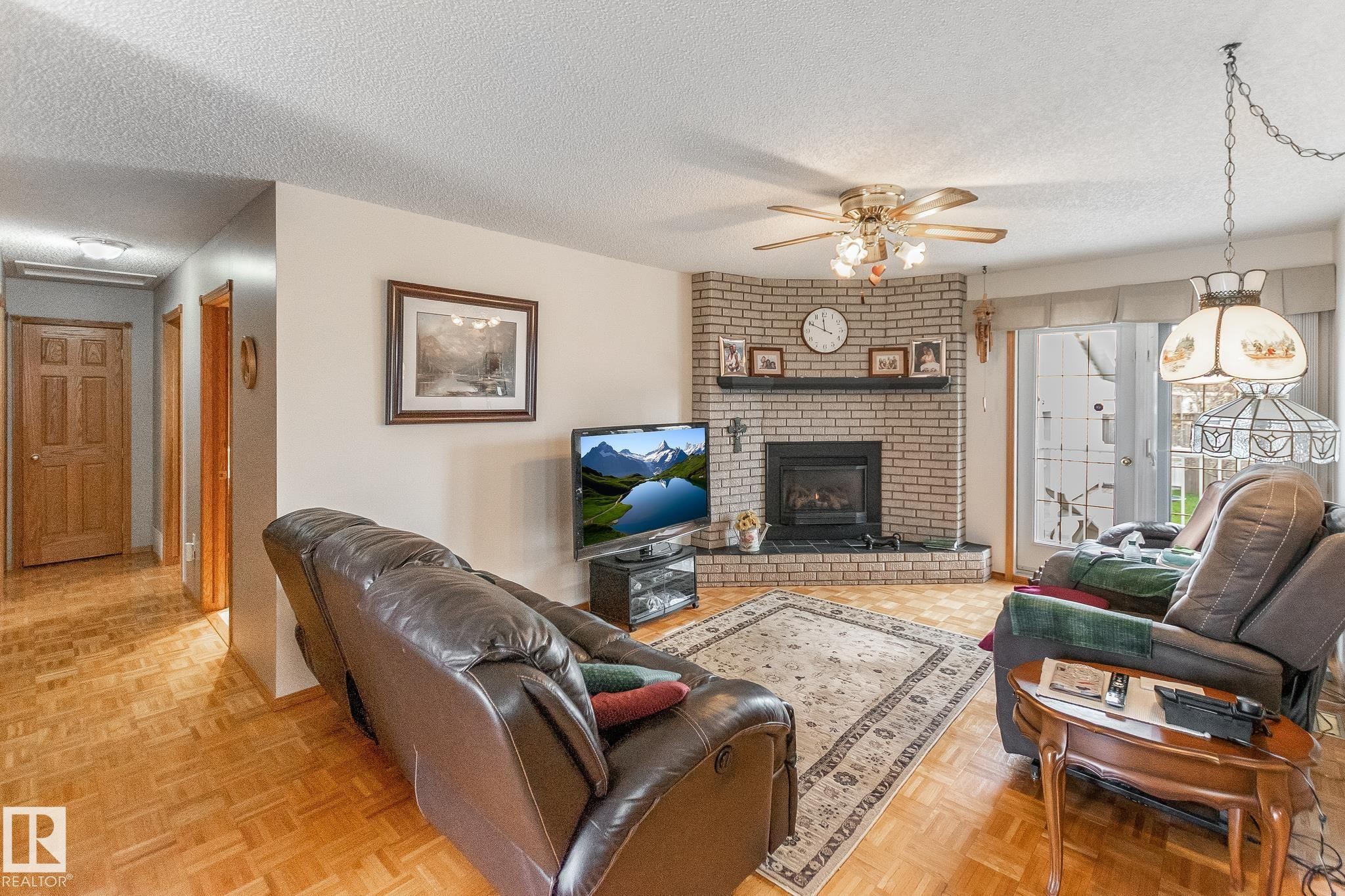 Living area featuring light wood-finish flooring and a brick fireplace with a dark hearth - 4611 Lakeshore Drive, Bonnyville Town, AB - Indoor Photo Showing Living Room With Fireplace