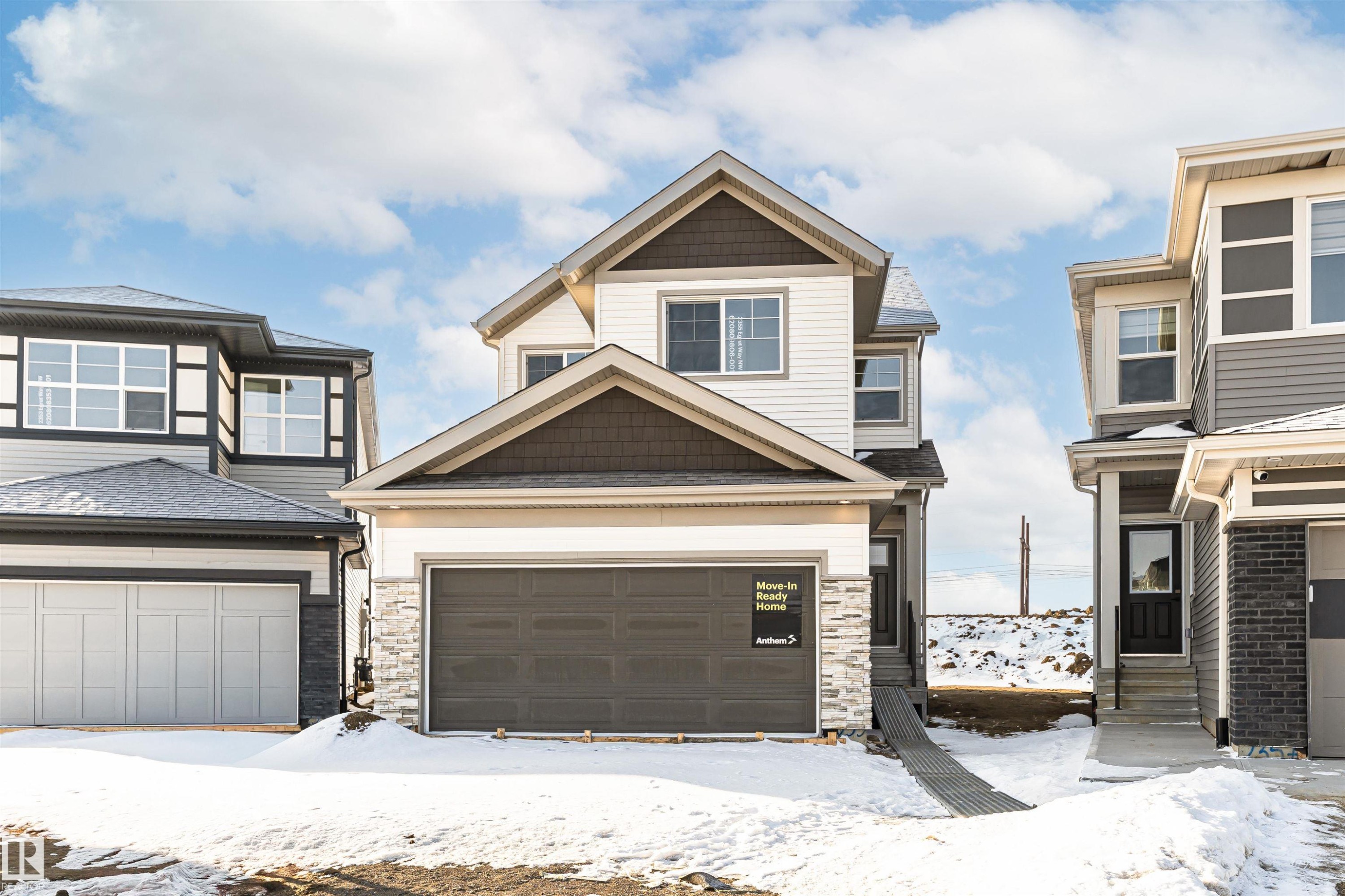 The property features light-colored siding with dark accents, a two-car garage, and a covered entry - 2355 Egret Way, Edmonton, AB - Outdoor With Facade