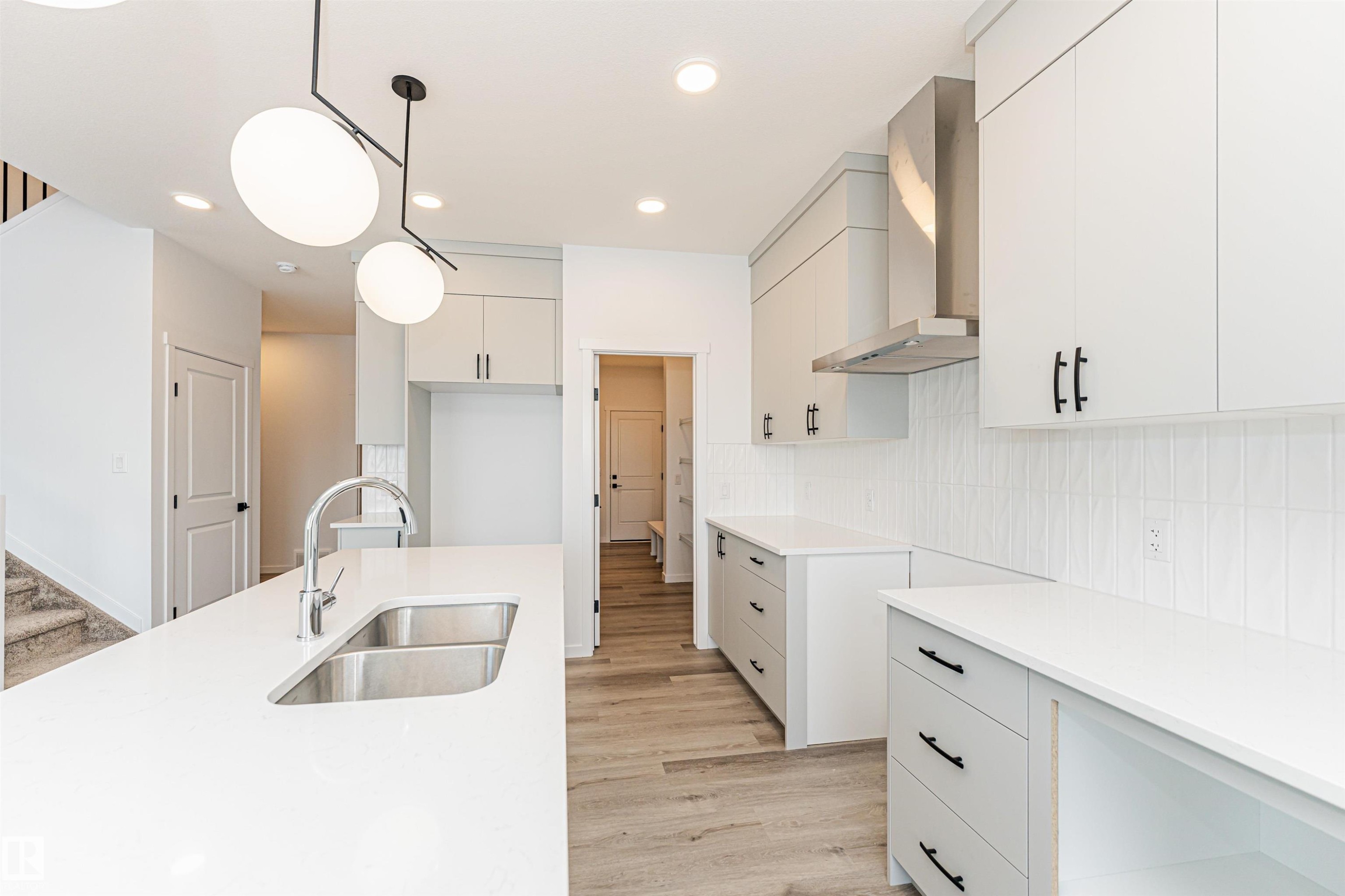 The kitchen features light-toned cabinetry, light countertops, and a subway tile backsplash - 2355 Egret Way, Edmonton, AB - Indoor Photo Showing Kitchen With Double Sink