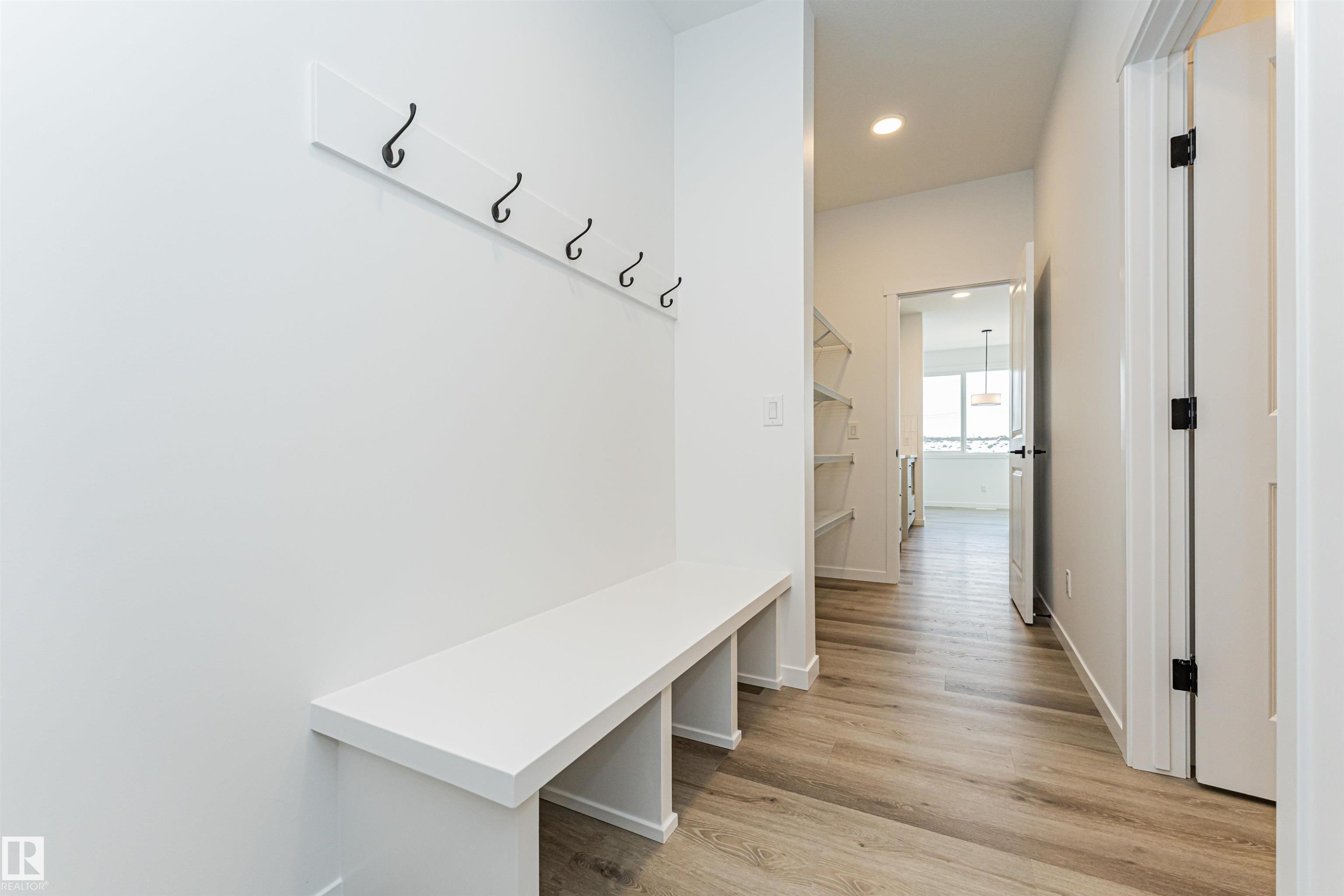 Entryway featuring a built-in bench, wall-mounted coat hooks, and light wood-look flooring - 2355 Egret Way, Edmonton, AB - Indoor Photo Showing Other Room