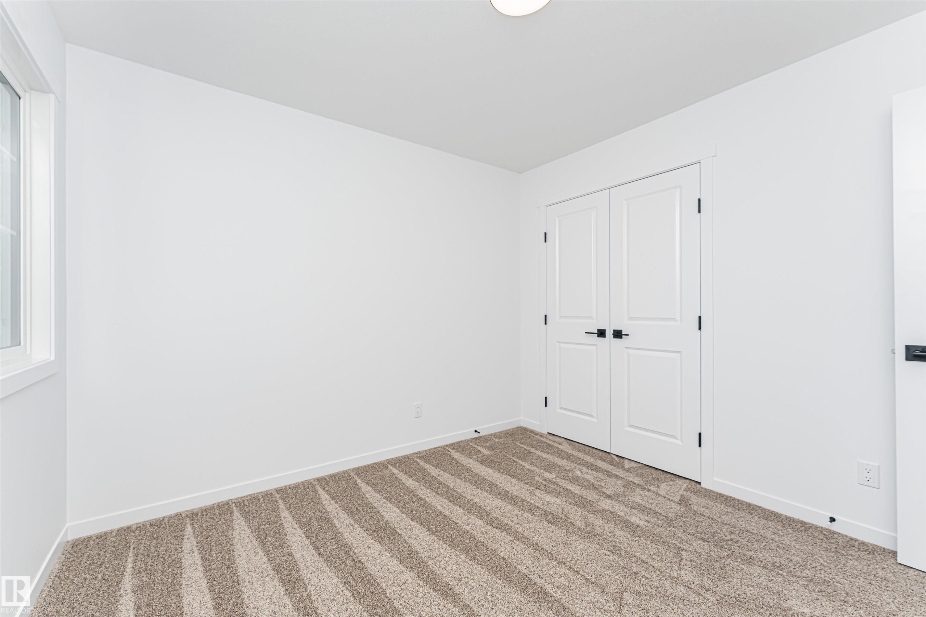 This room features bright white walls, a window providing natural light, and patterned carpeting - 2355 Egret Way, Edmonton, AB - Indoor Photo Showing Other Room
