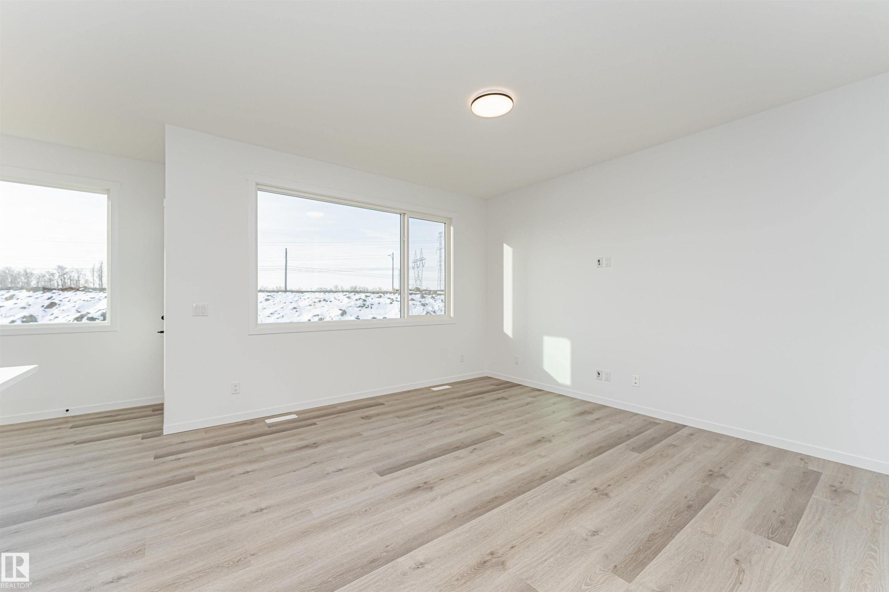 Spacious room featuring light wood flooring, white walls, and large windows providing ample natural light - 2355 Egret Way, Edmonton, AB - Indoor Photo Showing Other Room