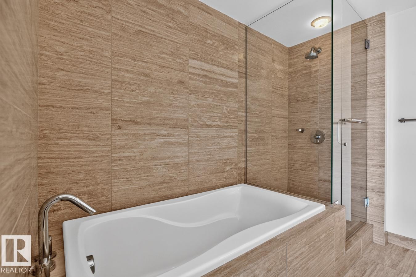 Modern bathroom featuring a built-in soaking tub with a polished chrome faucet, full-height tile surround, and a glass-enclosed shower with a rainfall showerhead - #407 2504 109 St Nw, Edmonton, AB - Indoor Photo Showing Bathroom