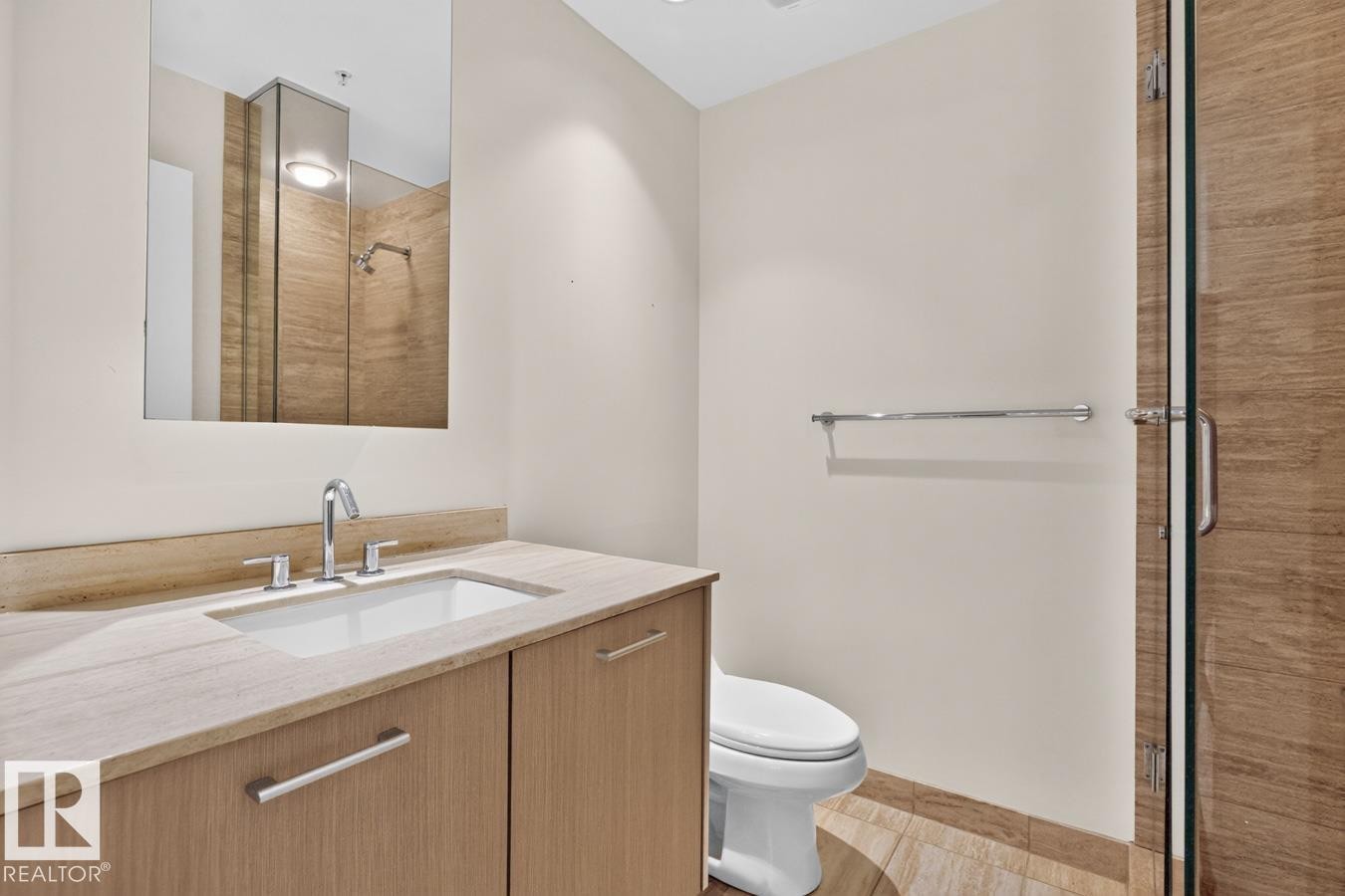 Contemporary bathroom featuring a wood-finish vanity with an integrated sink, stone countertop, and polished chrome fixtures - #407 2504 109 St Nw, Edmonton, AB - Indoor Photo Showing Bathroom