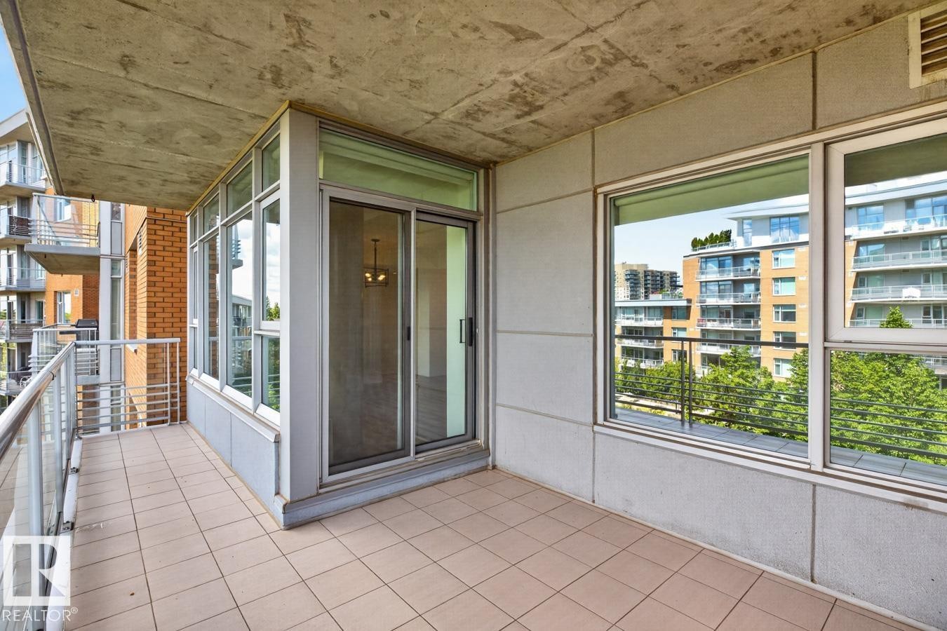 Private balcony featuring tiled flooring and a glass railing, providing access to the interior via a sliding glass door - #407 2504 109 St Nw, Edmonton, AB - Outdoor With Balcony With Exterior
