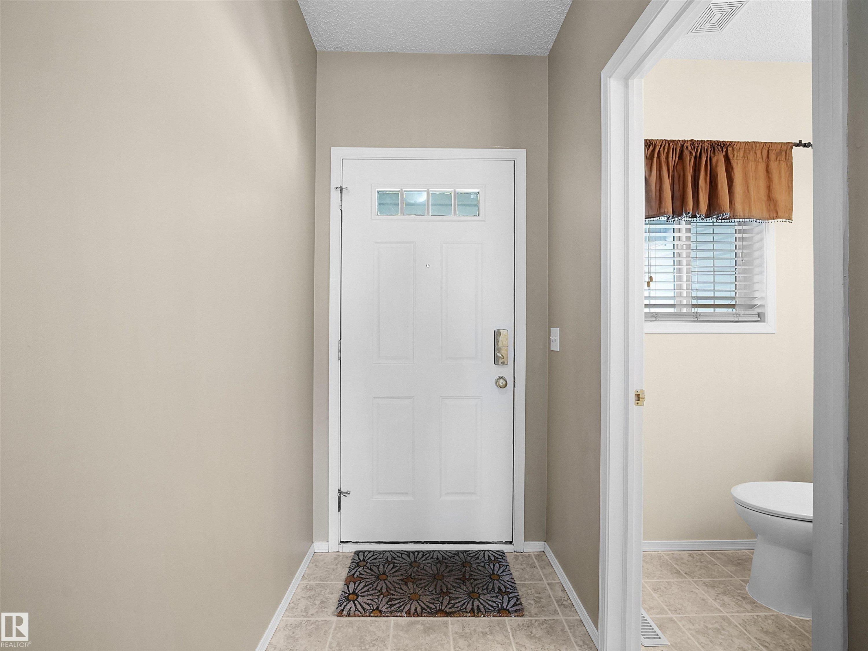 Entryway featuring a white paneled door with integrated glass lites and a neutral tile floor - 16121 131A Street, Edmonton, AB - Indoor Photo Showing Other Room