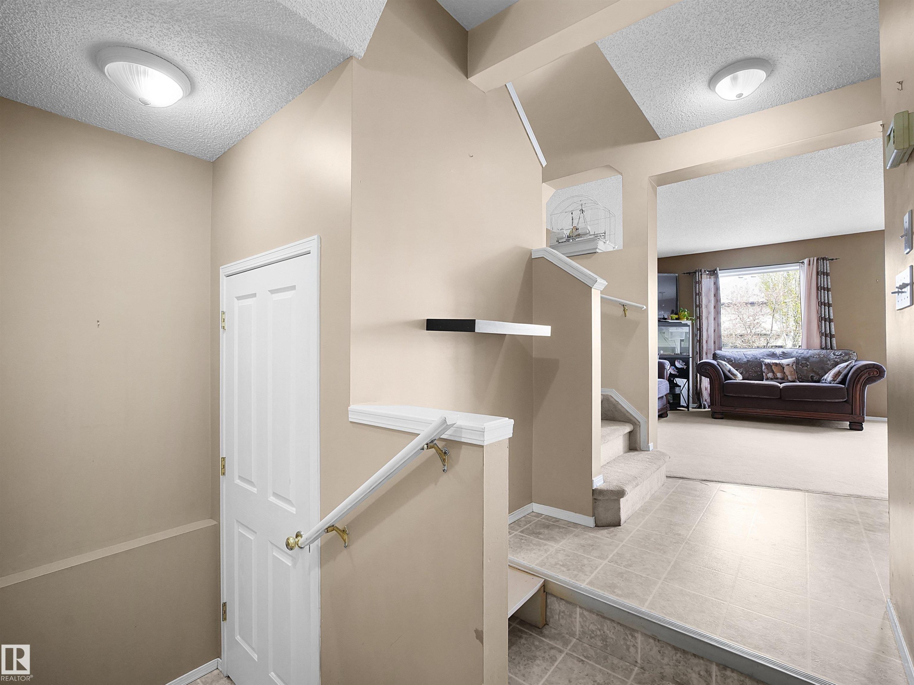 Multi-level entry foyer featuring tile flooring, neutral wall tones, and a staircase with a white railing - 16121 131A Street, Edmonton, AB - Indoor Photo Showing Other Room