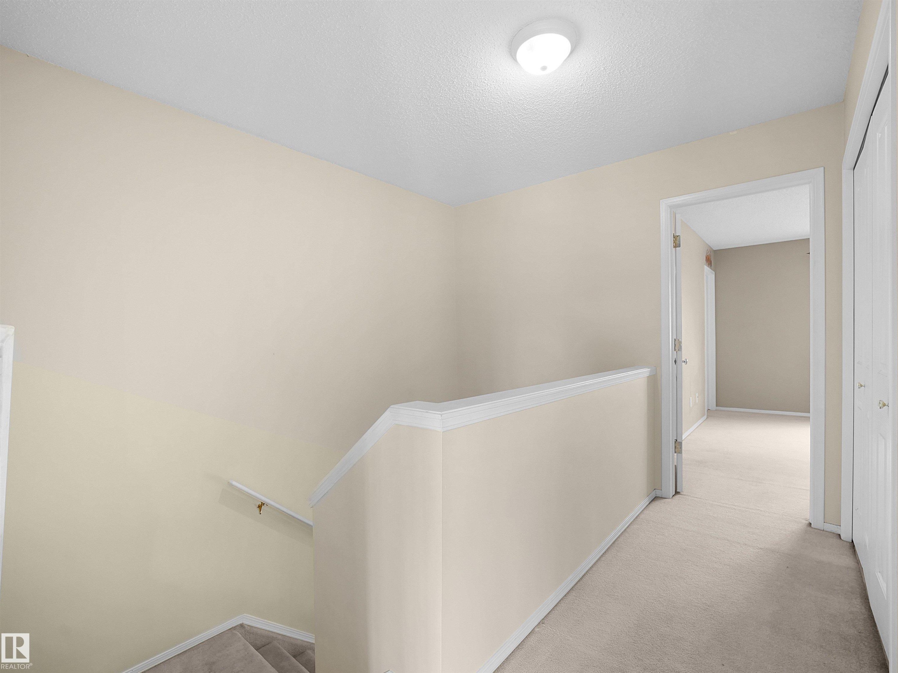 Interior hallway featuring light beige walls and neutral-toned carpeting - 16121 131A Street, Edmonton, AB - Indoor
