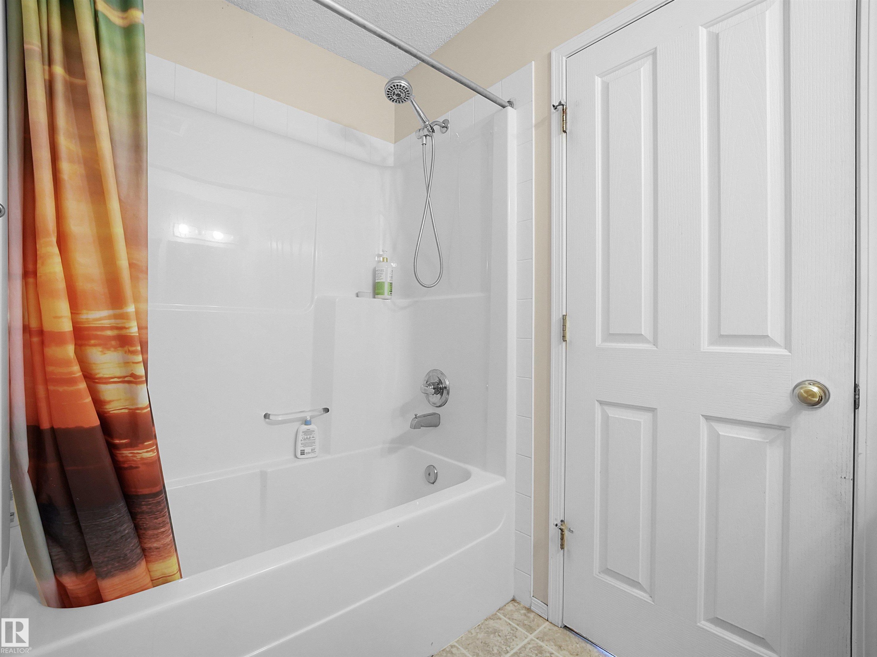 White bathtub and shower combination with a chrome shower head and fixtures - 16121 131A Street, Edmonton, AB - Indoor Photo Showing Bathroom