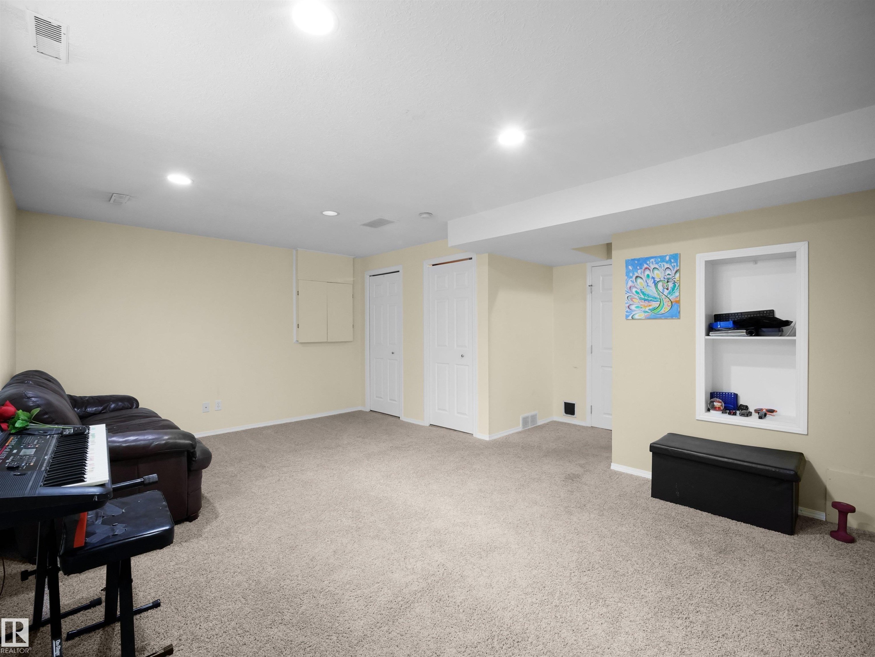 Spacious carpeted room featuring recessed lighting, a built-in shelving unit, and multiple white panel doors - 16121 131A Street, Edmonton, AB - Indoor Photo Showing Basement