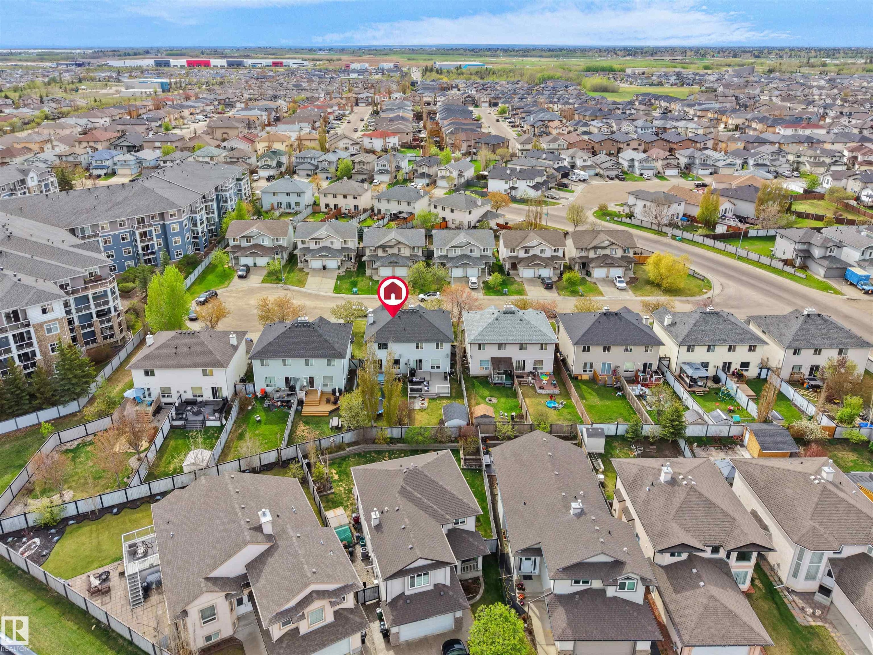 Aerial perspective showcasing a residential neighborhood with detached homes featuring shingled roofs and private backyards, alongside multi-story apartment buildings - 16121 131A Street, Edmonton, AB - Outdoor With View
