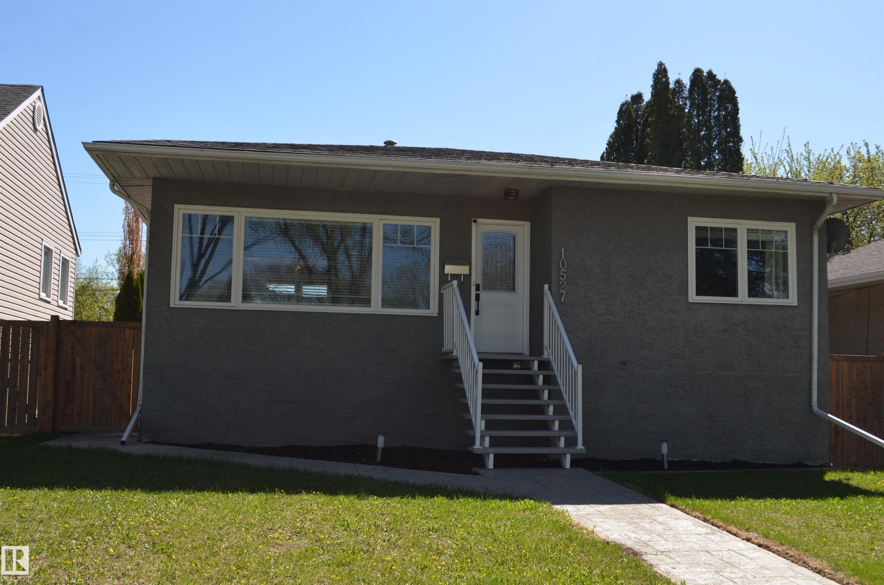 Exterior featuring gray stucco siding, white trim windows, and a white front entry door with side light - 10527 81 Street, Edmonton, AB - Outdoor