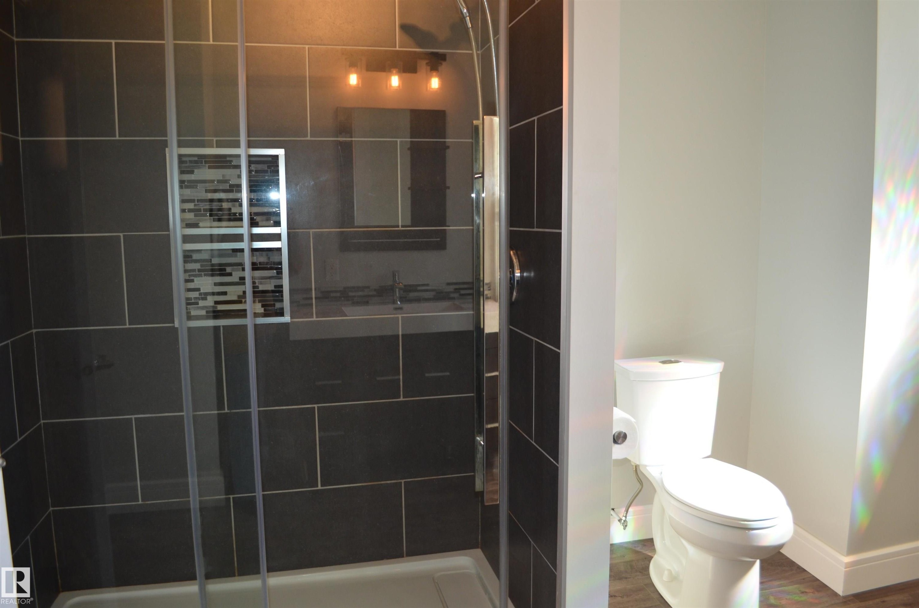 Shower enclosure with clear glass door, dark rectangular tile surround, and a mosaic tile niche - 10527 81 Street, Edmonton, AB - Indoor Photo Showing Bathroom