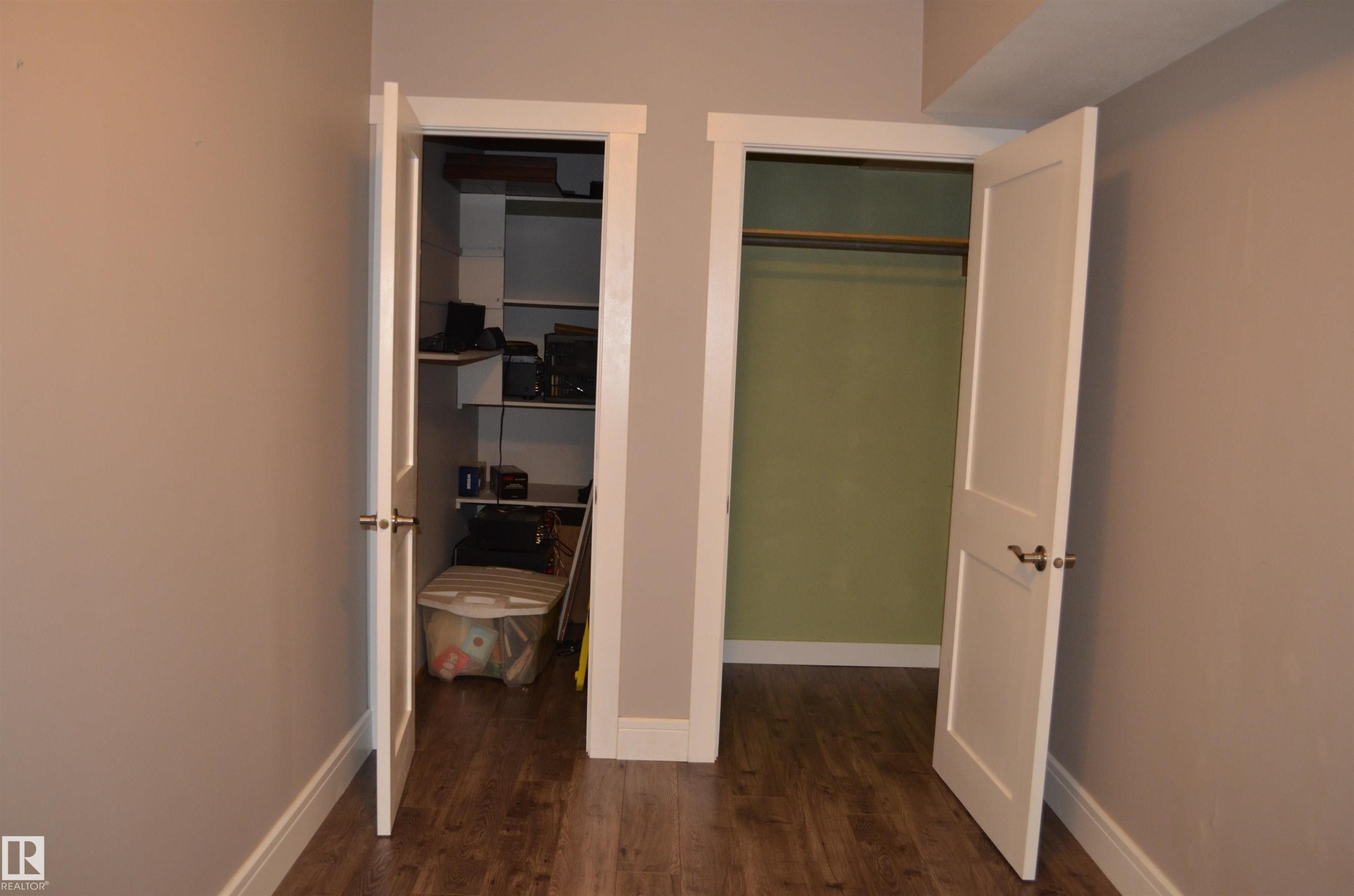 Two interior doorways with contrasting closet interiors and wood-finish flooring - 10527 81 Street, Edmonton, AB - Indoor Photo Showing Other Room