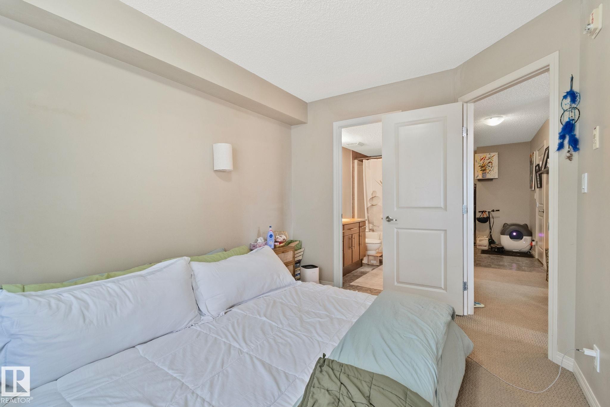Bedroom featuring neutral wall paint, carpet flooring, a wall-mounted light fixture, and two panel doors - 206 103 Ambleside Drive, Edmonton, AB - Indoor Photo Showing Bedroom