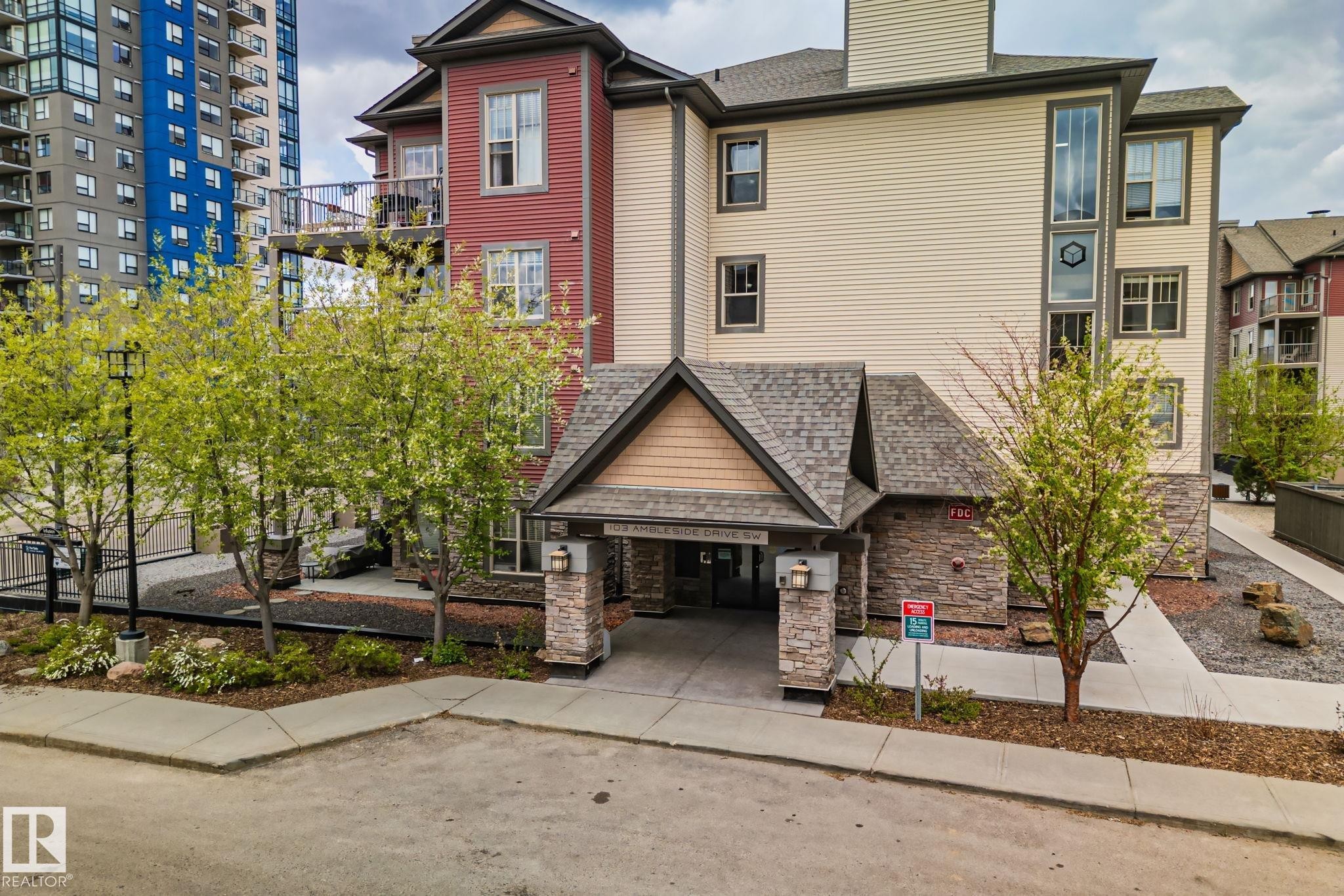Multi-story building featuring stone accents, a covered entry, and balconies - 206 103 Ambleside Drive, Edmonton, AB - Outdoor With Balcony