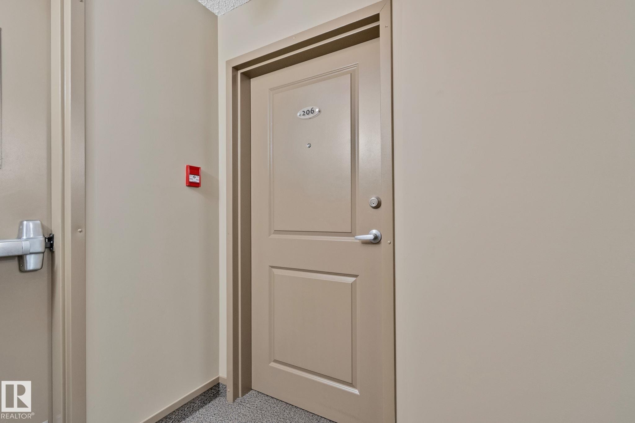 Entry door with panel detailing and silver-toned hardware - 206 103 Ambleside Drive, Edmonton, AB - Indoor Photo Showing Other Room