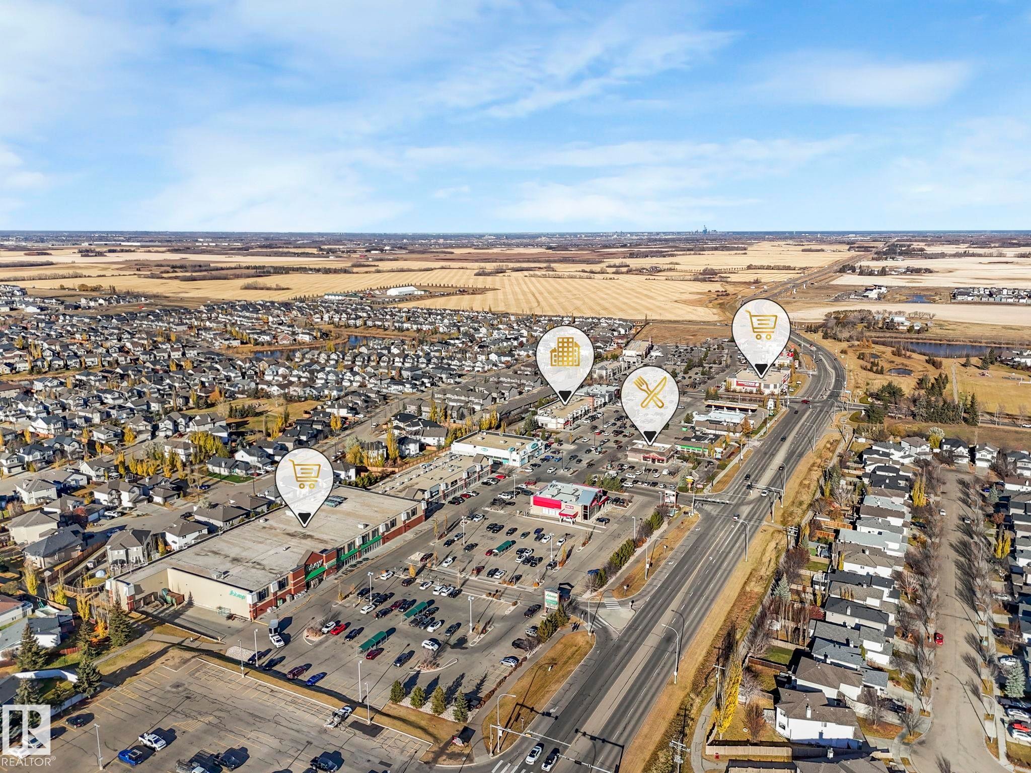 Aerial perspective of a developed neighborhood featuring residential areas, commercial establishments, and open fields - 6613 62 Avenue, Beaumont, AB - Outdoor With View