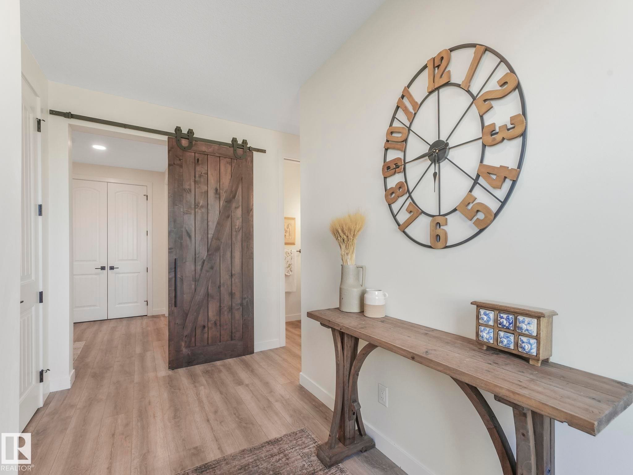 Hallway featuring a dark wood-finish barn door, light wood-finish flooring, and white interior walls - 6613 62 Avenue, Beaumont, AB - Indoor Photo Showing Other Room