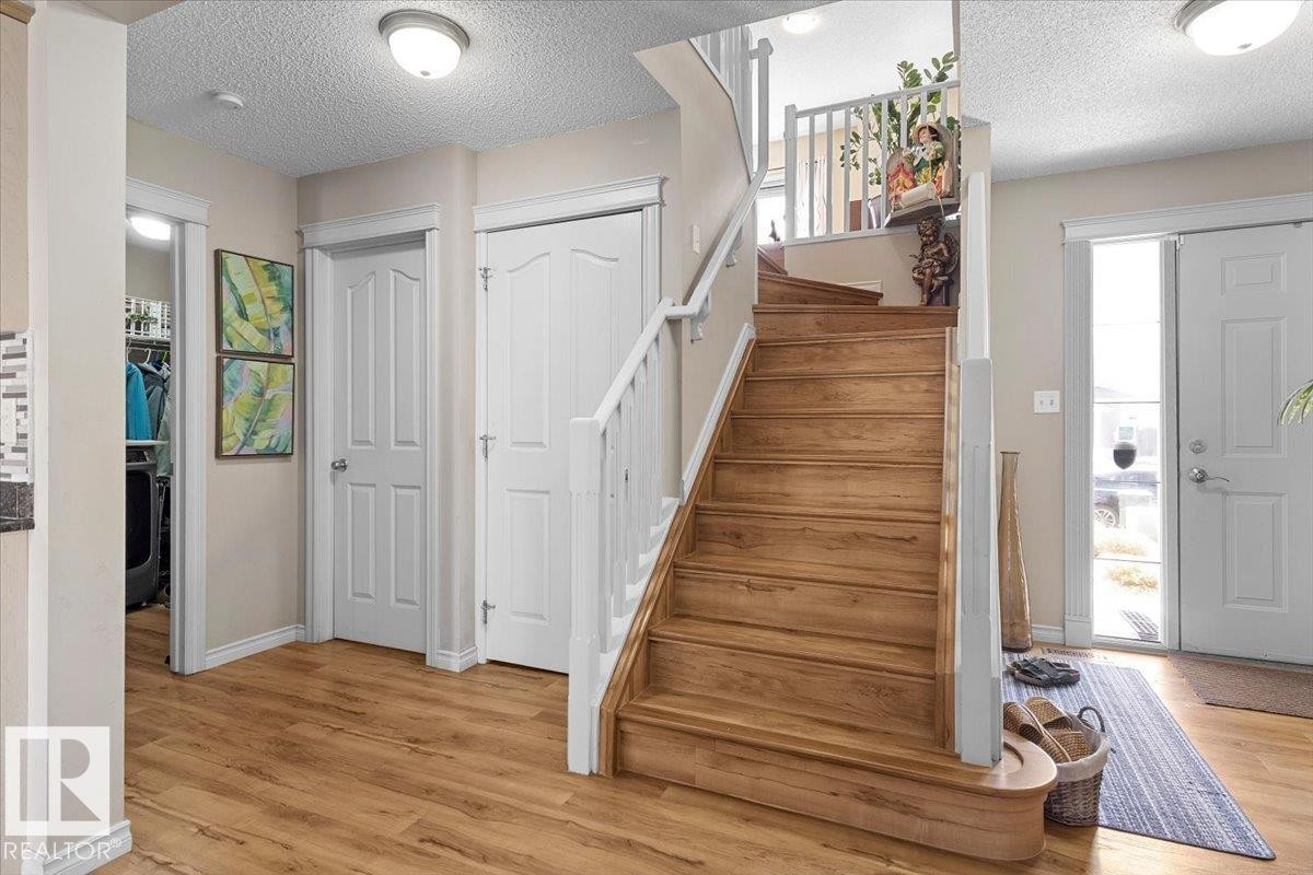 Staircase entry featuring wood-finish flooring, white spindle railing, and a paneled door - 3356 25 Ave, Edmonton, AB - Indoor Photo Showing Other Room