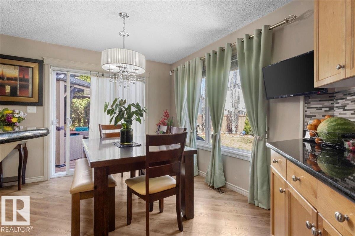 Dining area with wood-finish flooring and a multi-light chandelier - 3356 25 Ave, Edmonton, AB - Indoor Photo Showing Dining Room