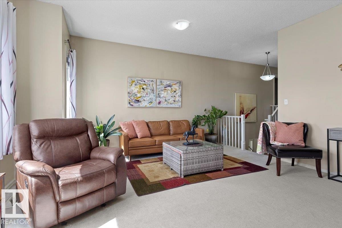 Open-concept living area featuring light neutral wall colors, carpeted flooring, and a white wood railing - 3356 25 Ave, Edmonton, AB - Indoor Photo Showing Living Room