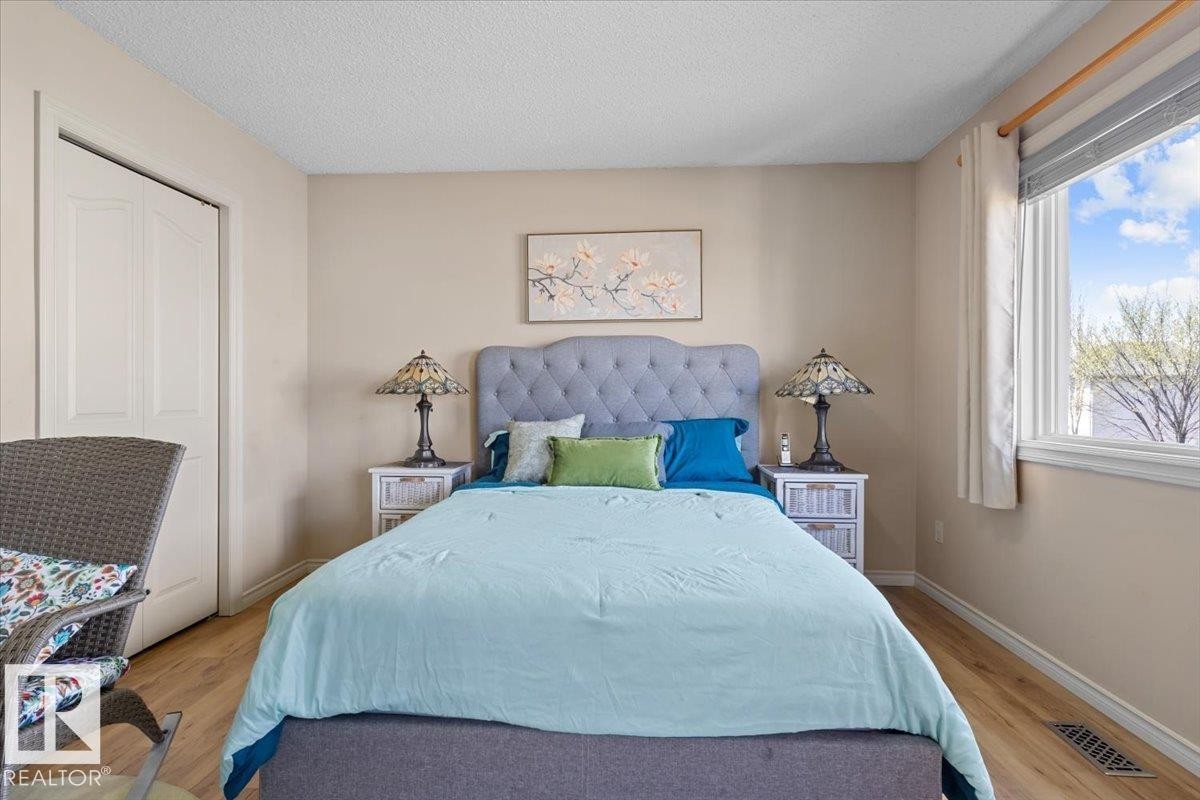 Bedroom featuring wood-finish flooring, a double-door closet, a large window, and light-toned wall paint - 3356 25 Ave, Edmonton, AB - Indoor Photo Showing Bedroom