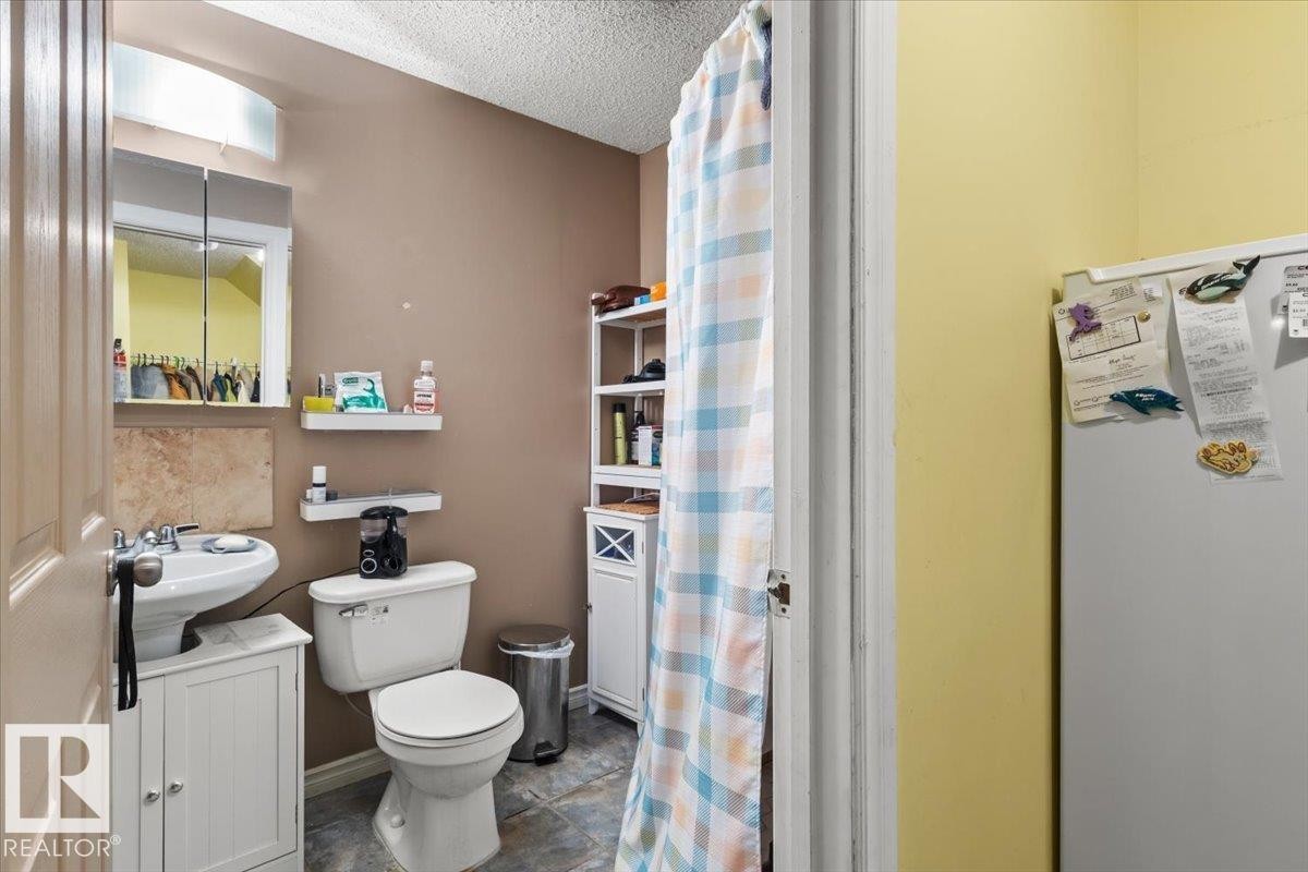 Pedestal sink with white vanity base, toilet, and tiled flooring - 3356 25 Ave, Edmonton, AB - Indoor Photo Showing Bathroom
