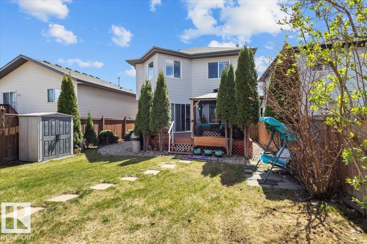 Expansive backyard featuring a manicured lawn, stepping stones, wooden privacy fencing, and a built-in storage shed - 3356 25 Ave, Edmonton, AB - Outdoor