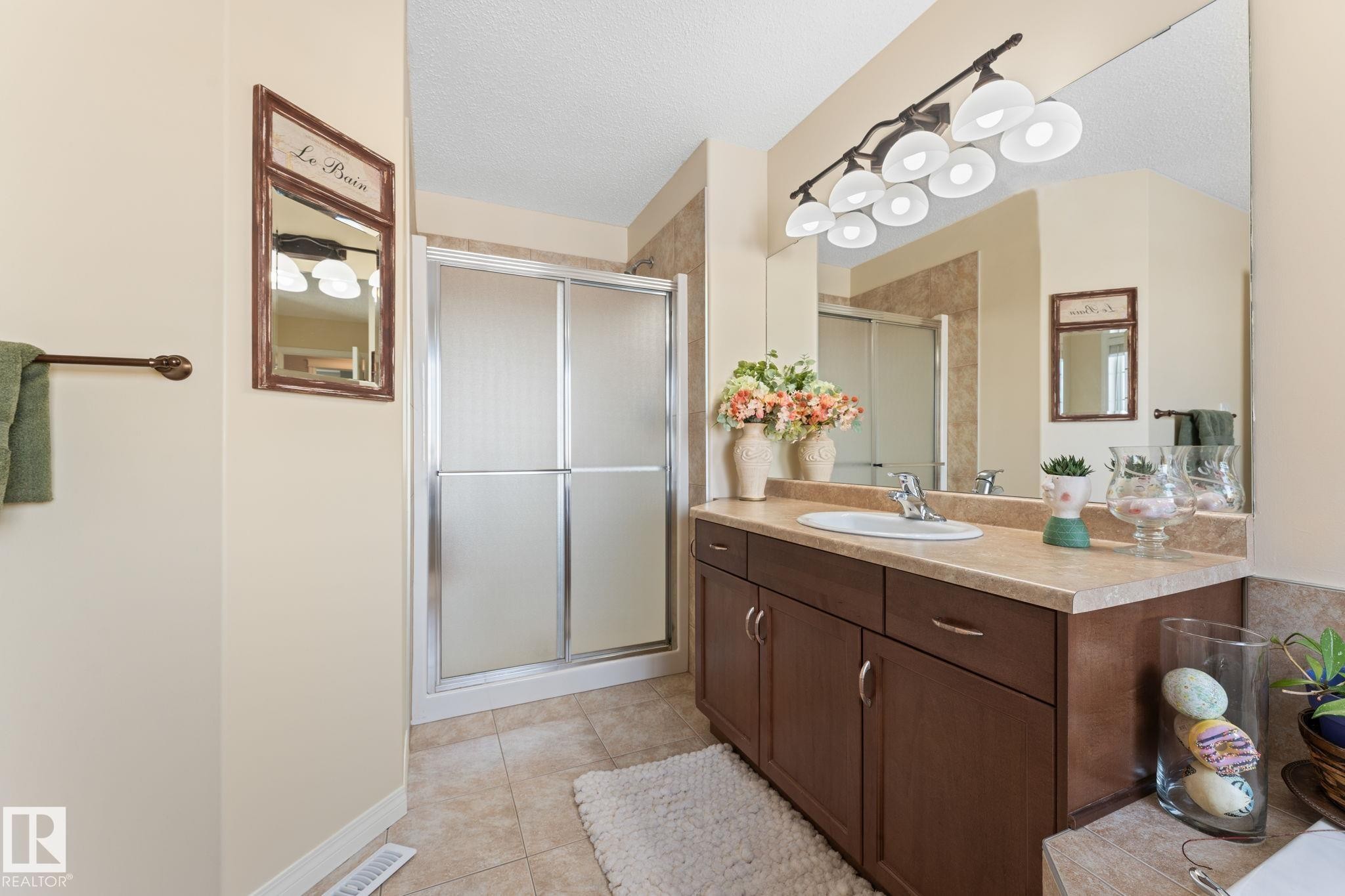 Bathroom featuring a vanity with a light-colored countertop, integrated sink, and dark wood-finish cabinetry - 112 Lakeland Point(E), Beaumont, AB - Indoor Photo Showing Bathroom