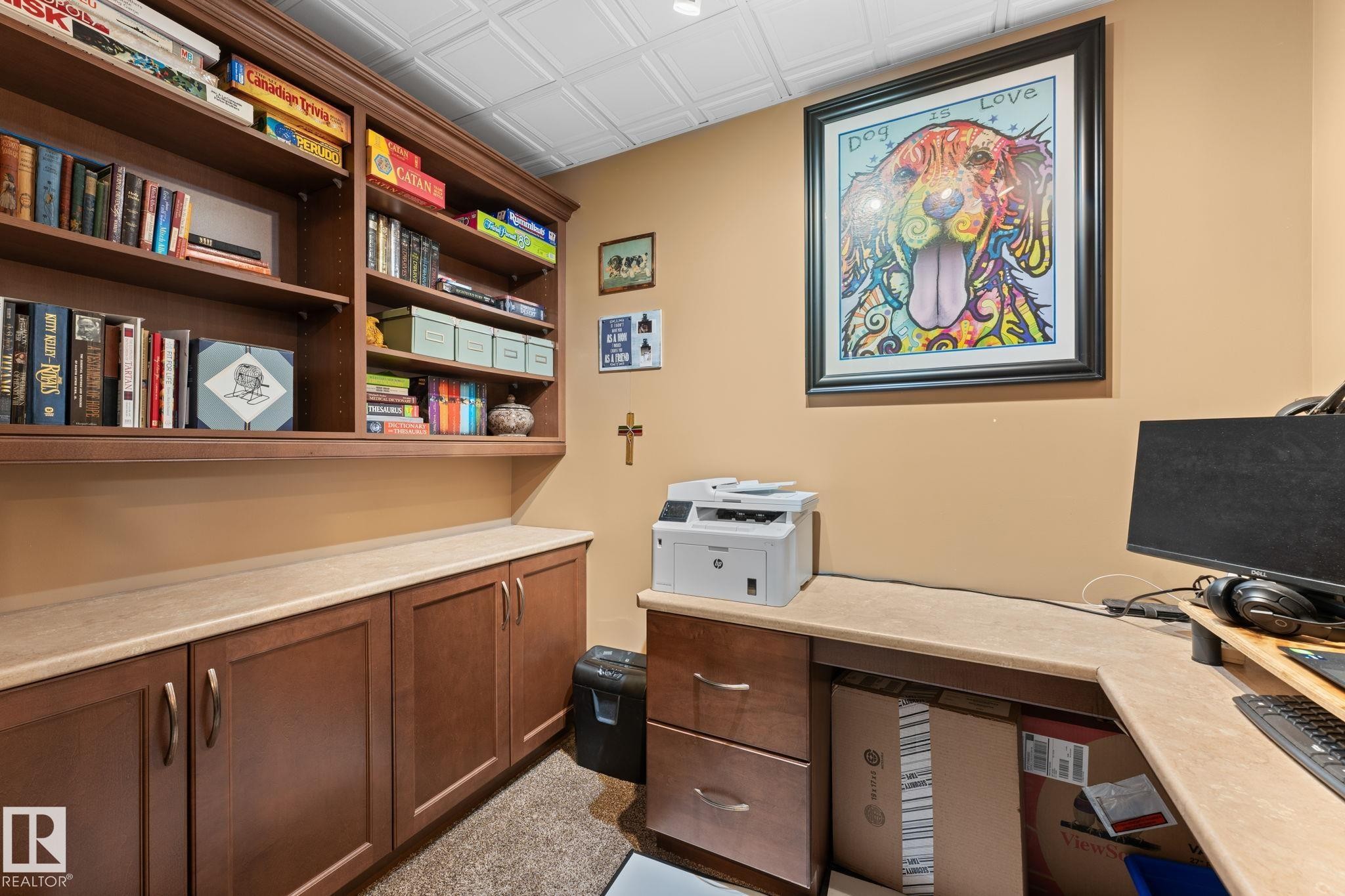 Built-in cabinetry with wood-finish doors and drawers, featuring extensive shelving, light-toned countertops, and a textured ceiling - 112 Lakeland Point(E), Beaumont, AB - Indoor Photo Showing Office