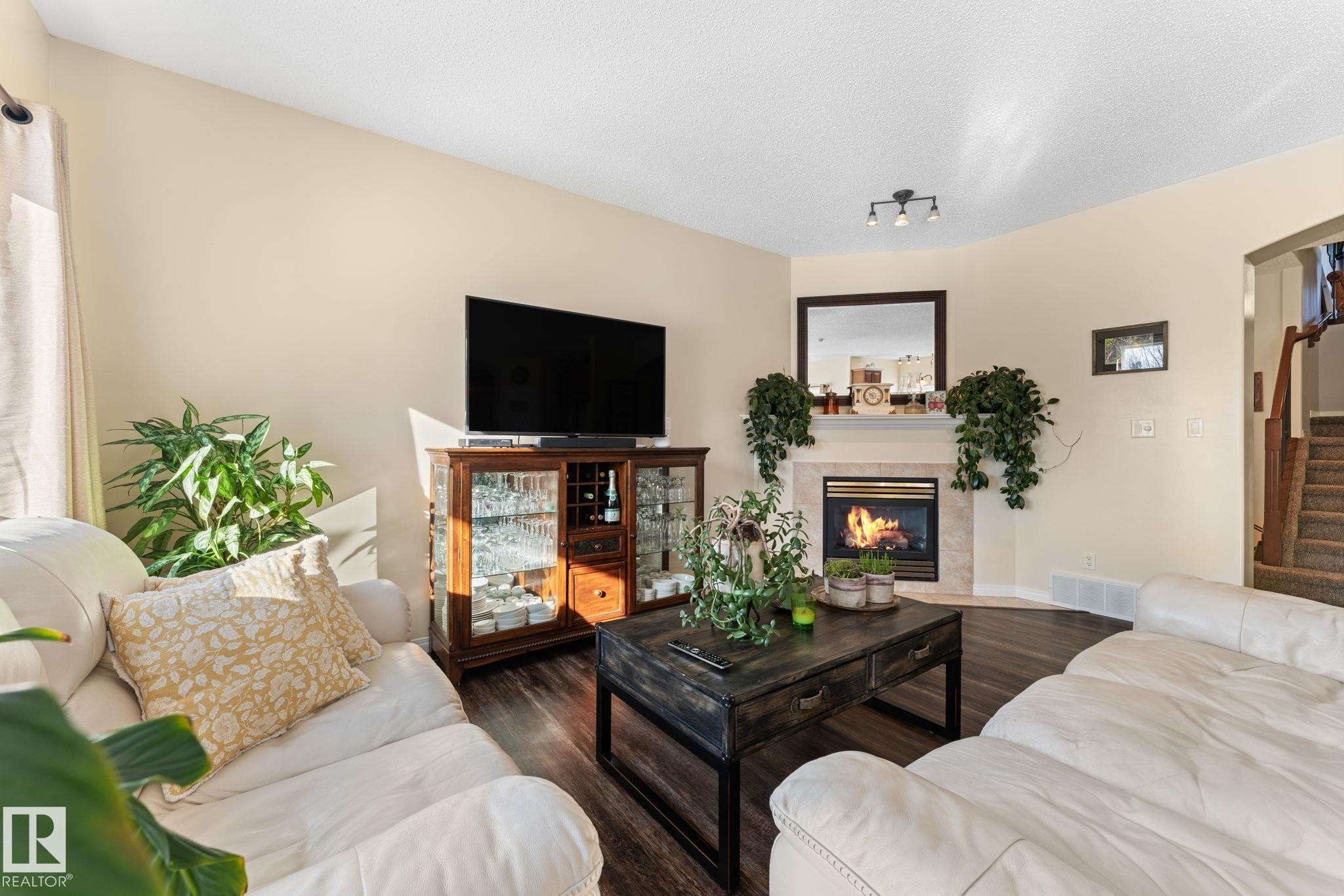 Corner fireplace with a light-toned tile surround and mantel - 112 Lakeland Point(E), Beaumont, AB - Indoor Photo Showing Living Room With Fireplace