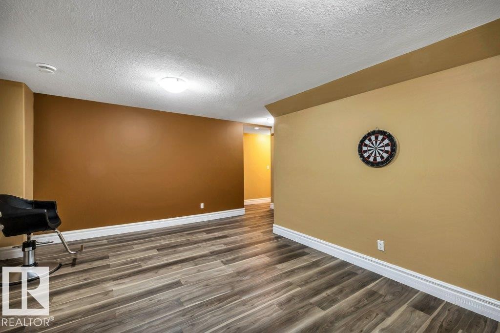 Spacious room featuring wood-finish flooring, two-tone wall paint, white baseboards, and a ceiling-mounted light fixture - 816 Wildwood Crescent, Edmonton, AB - Indoor Photo Showing Other Room