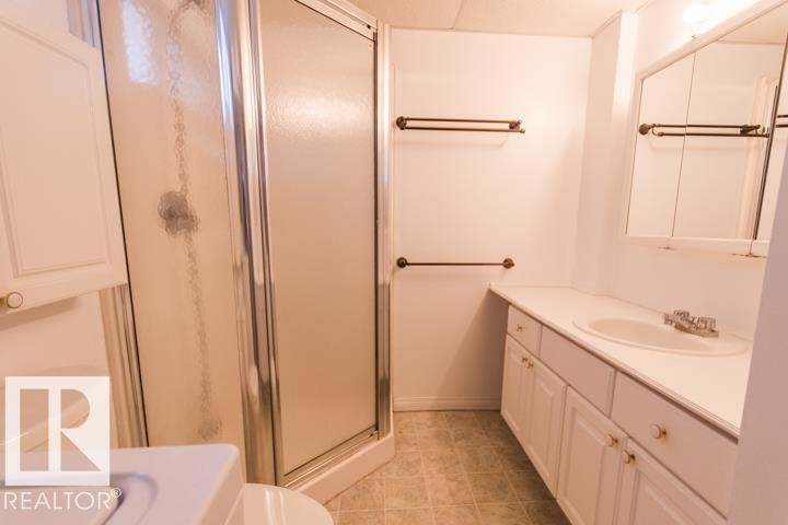 The bathroom features a standing shower with a clear and frosted glass enclosure, a vanity with a white countertop and integrated sink, and a mirrored medicine cabinet - 10806 64 Avenue, Edmonton, AB - Indoor Photo Showing Bathroom