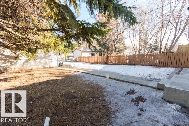 The property features a spacious yard with a concrete patio, a wooden fence, and mature trees - 10806 64 Avenue, Edmonton, AB - Outdoor