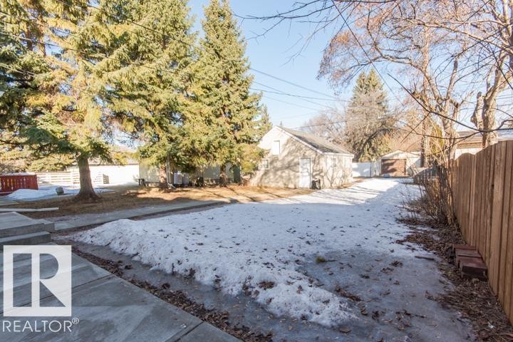 The property includes a paved walkway, a wooden fence, and mature trees - 10806 64 Avenue, Edmonton, AB - Outdoor