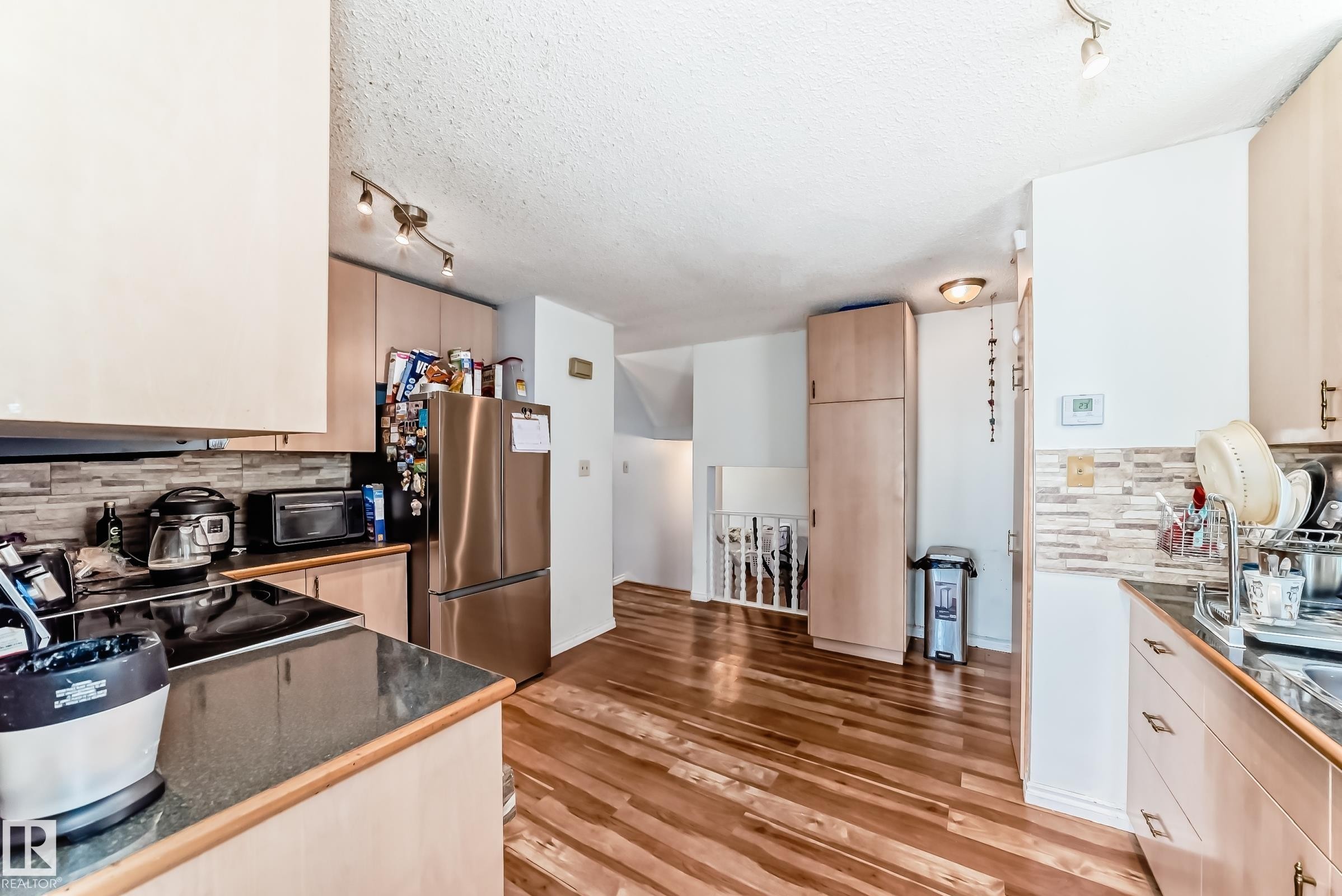 Modern kitchen featuring wood-finish flooring, light wood cabinetry, stone-look countertops, and a full stainless steel appliance package - 1804 51 Street Nw, Edmonton, AB - Indoor Photo Showing Kitchen